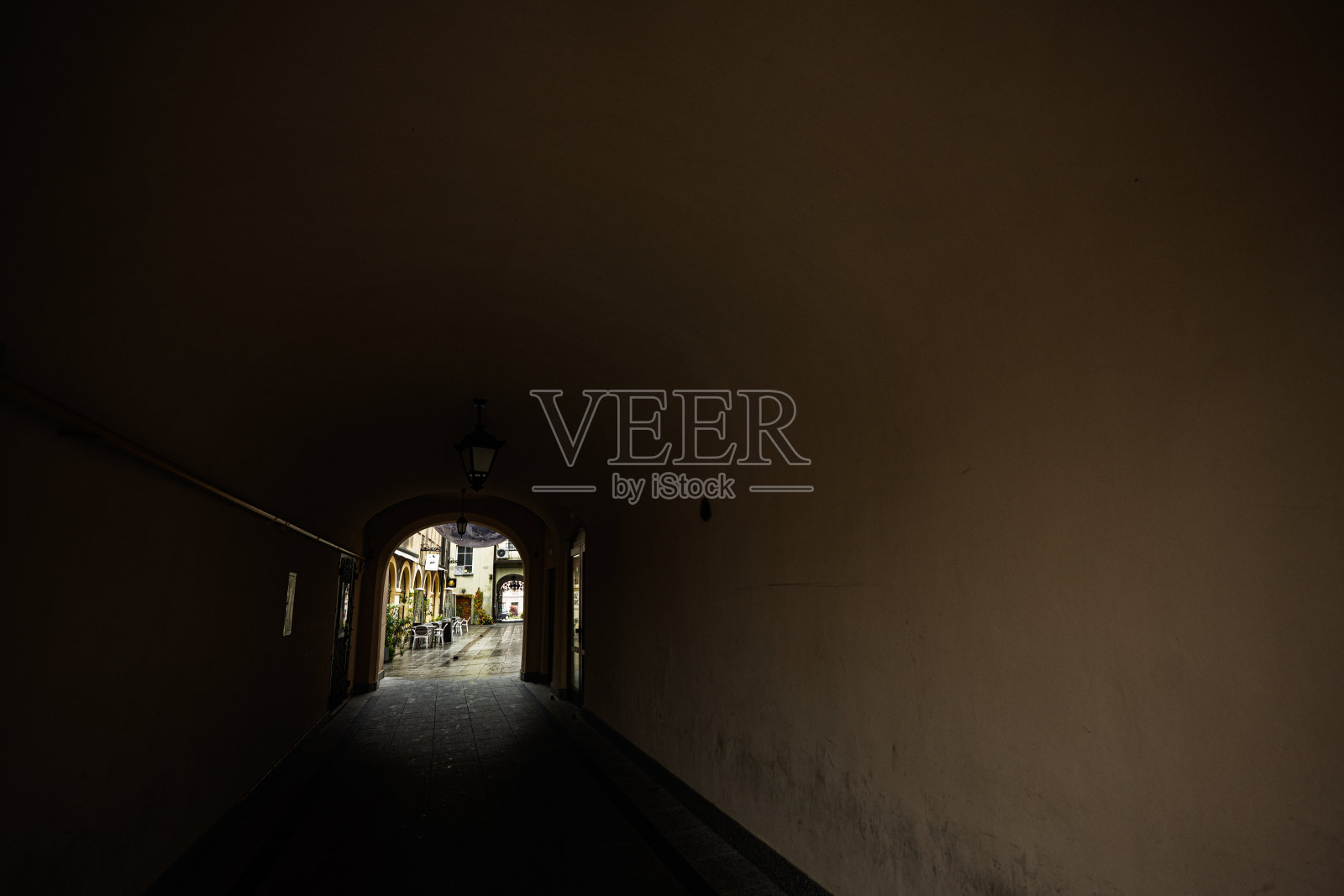 波兰塔尔努夫，一条狭窄的隧道穿过拱门，通向阳光明媚的街道照片摄影图片