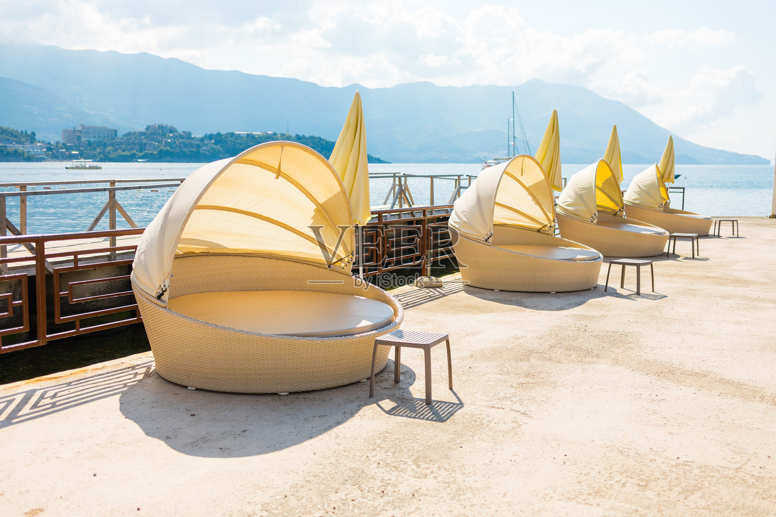 度假村码头上的现代遮阳躺椅，沐浴在明亮的夏日阳光下。户外休闲、尊贵舒适和滨水旅游。照片摄影图片