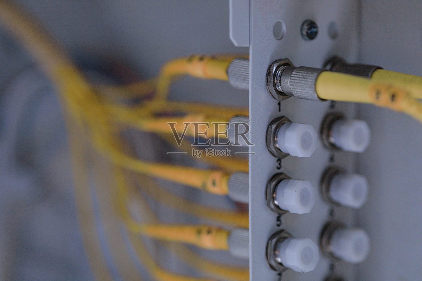 特写镜头，展示了连接到配线架或分配箱的黄色光纤线缆。这说明了高速互联网、电信网络和数据中心必不可少的硬件。照片摄影图片