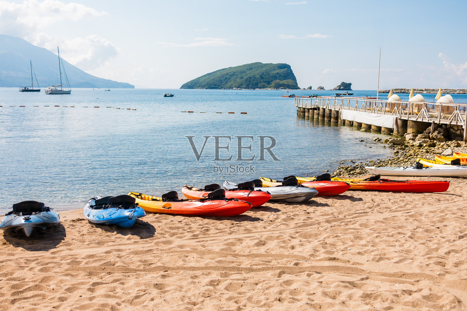 五颜六色的皮划艇整齐地排列在沙滩上。黑山布德瓦的夏季休闲、探险旅游和海滨运动。照片摄影图片