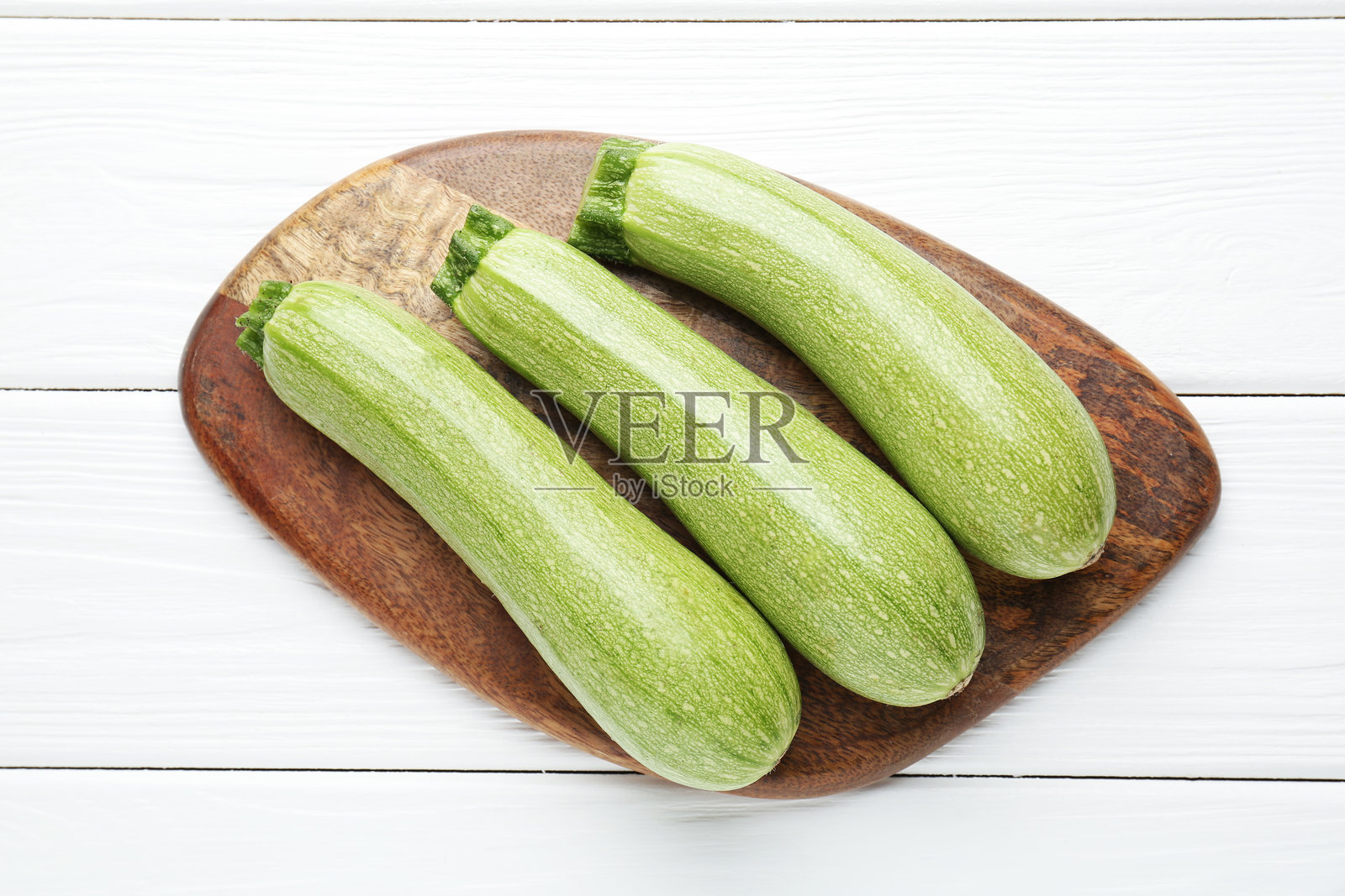新鲜成熟的西葫芦放在白色木桌上，俯视视角照片摄影图片
