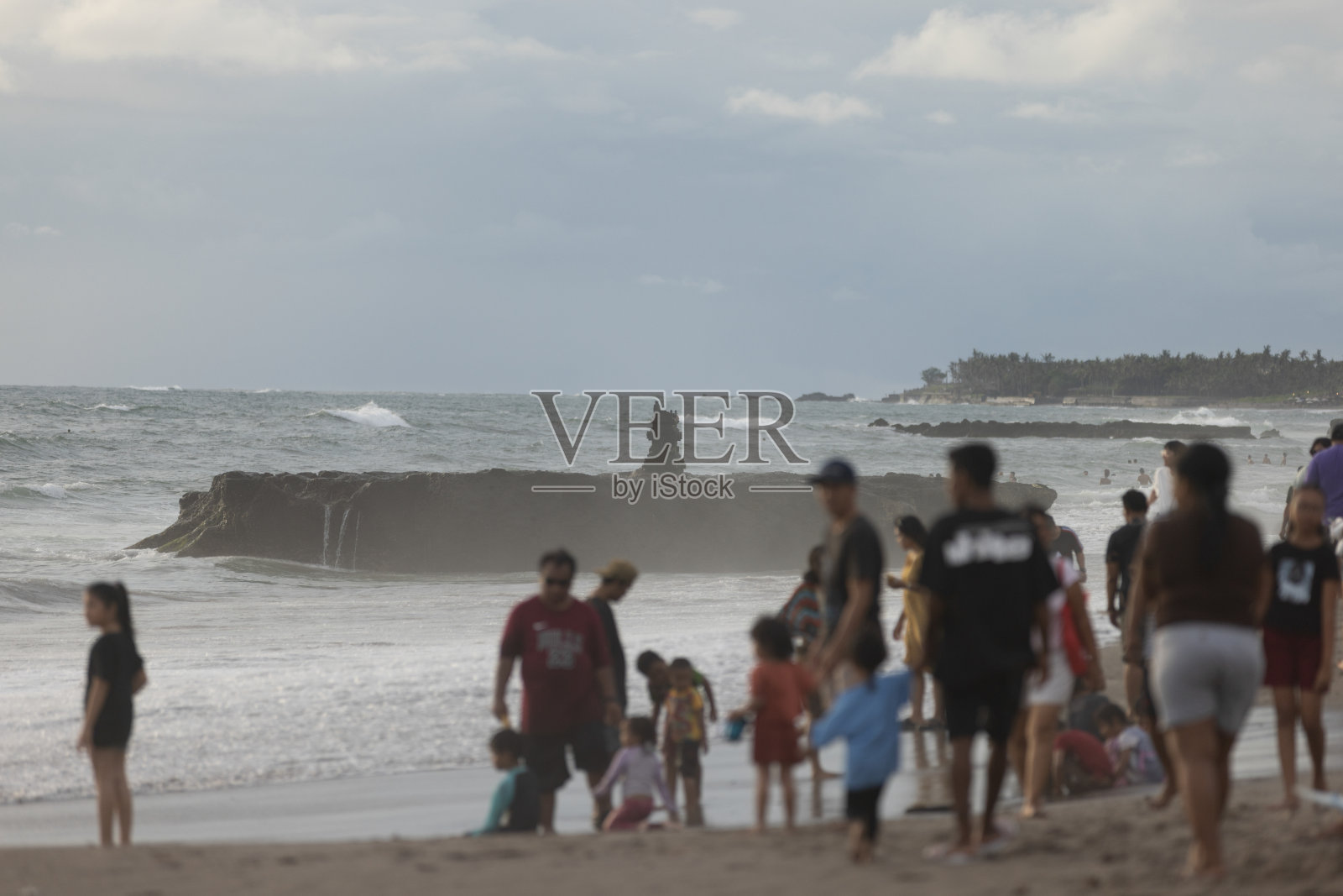 一群人在日落时分漫步在沙滩上。照片摄影图片