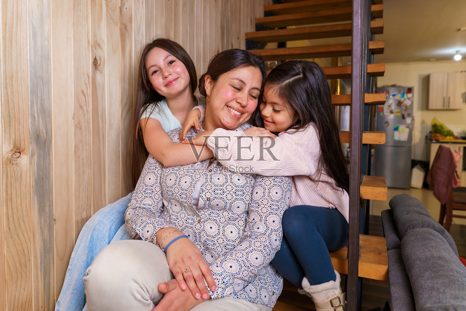 母亲在家中拥抱年幼的女儿们照片摄影图片