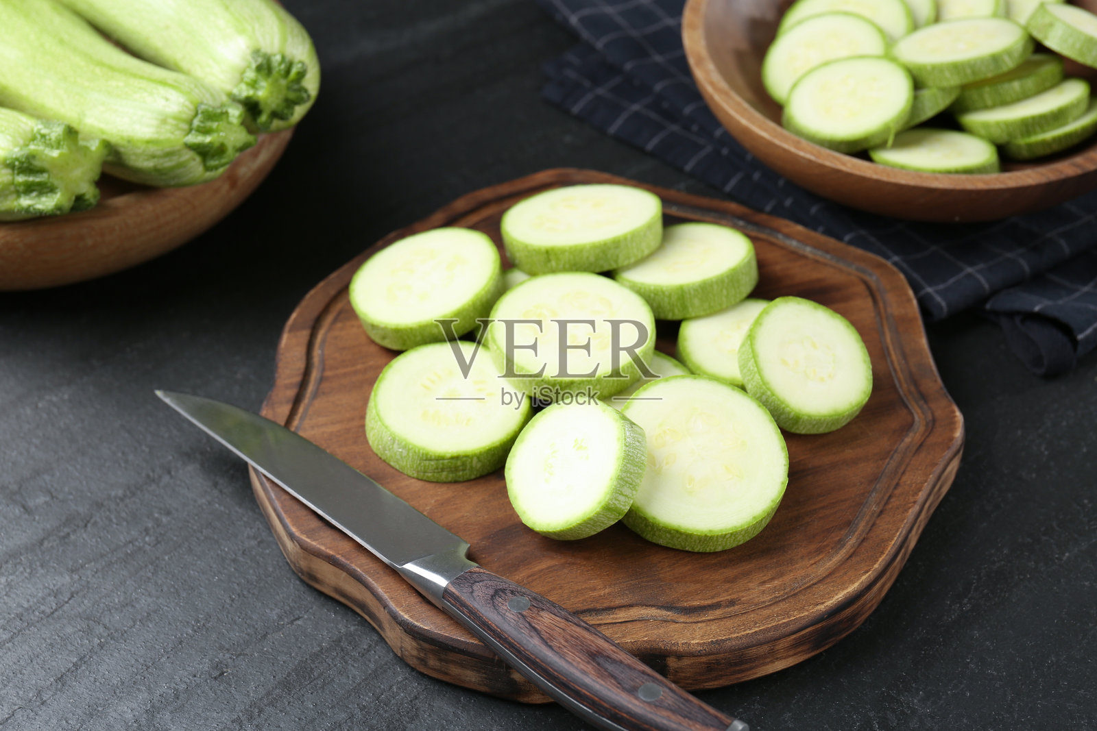 特写：黑色纹理桌面上放着一把刀和新鲜成熟的西葫芦照片摄影图片