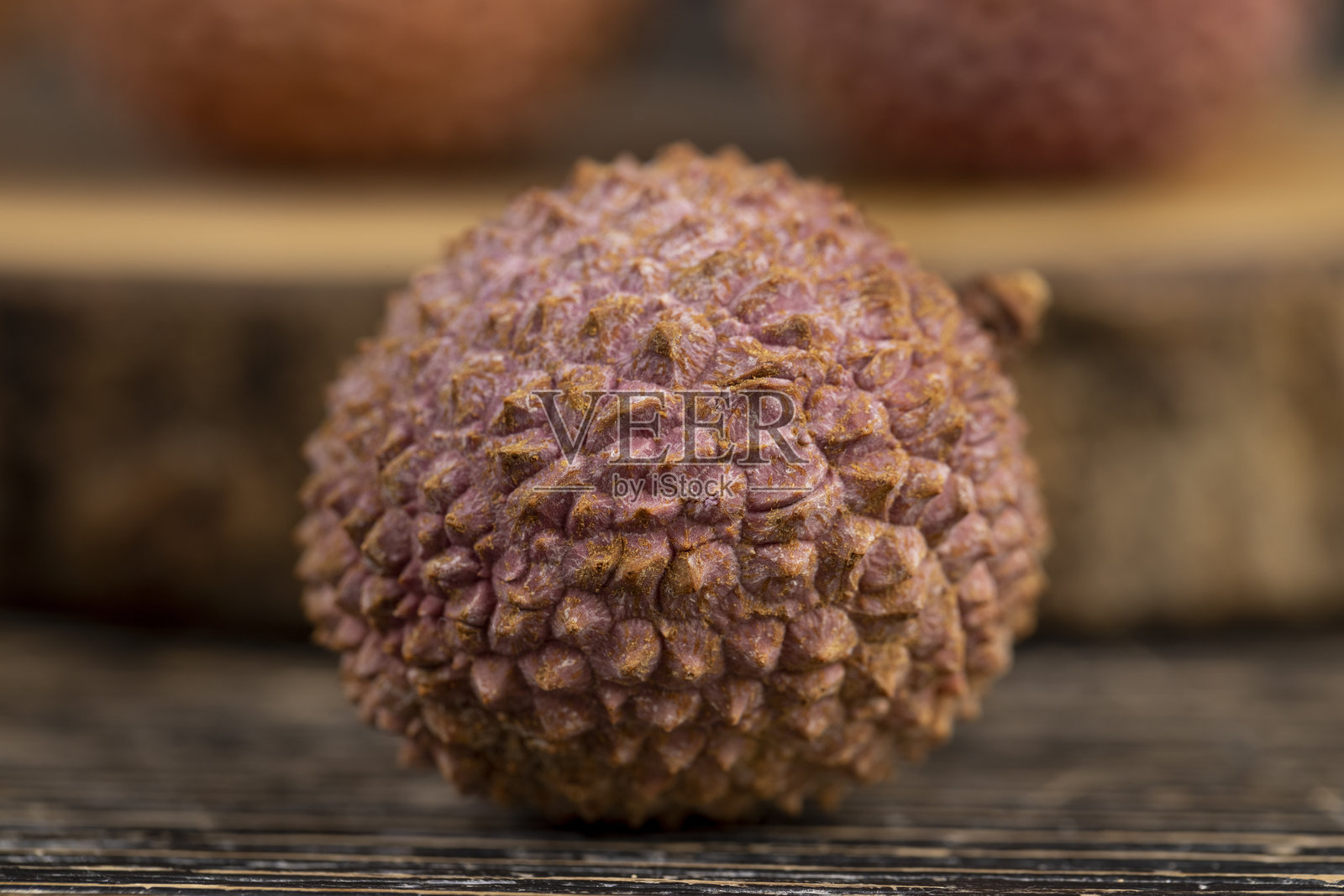 成熟的荔枝散落在木桌上，成熟的红皮荔枝果，粗糙纹理的荔枝皮特写照片摄影图片