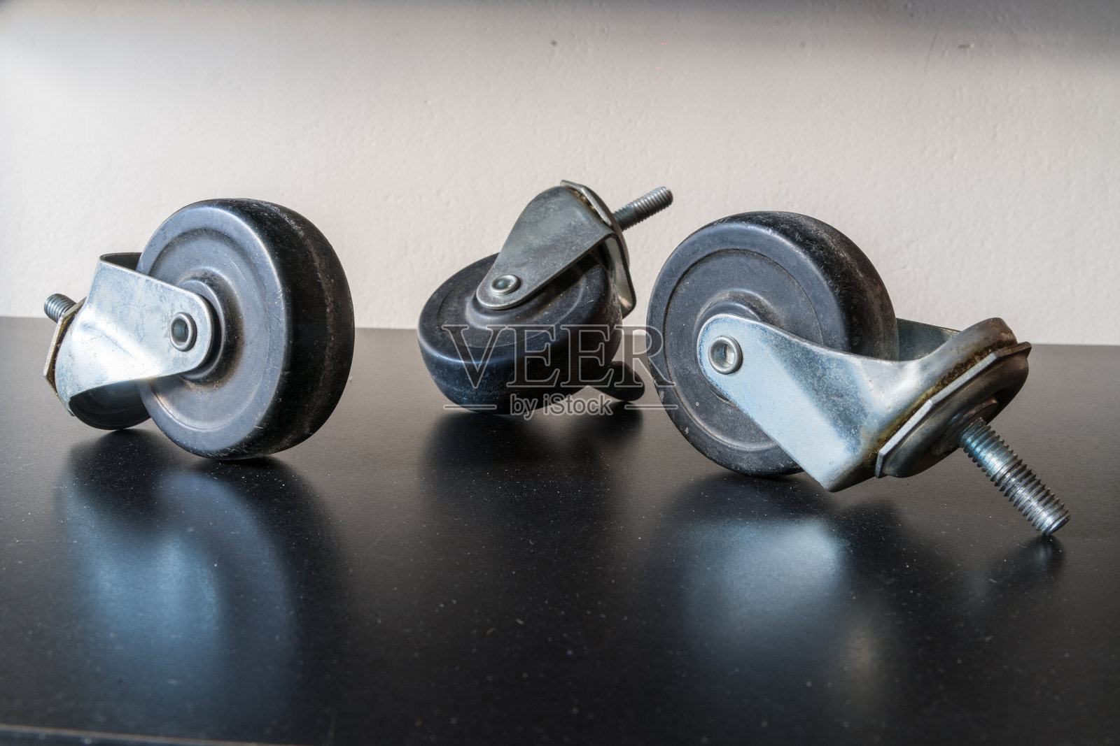 深色表面上的三个金属橡胶家具脚轮照片摄影图片