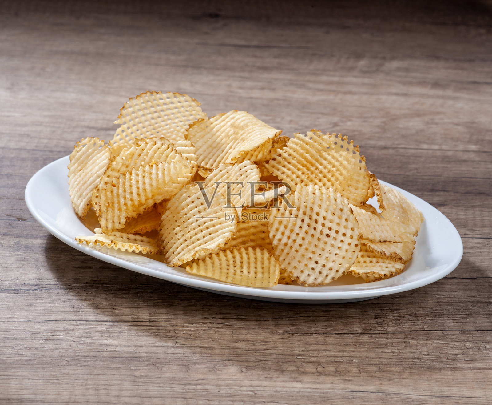 白色盘子里的华夫格薯片放在木质表面上照片摄影图片