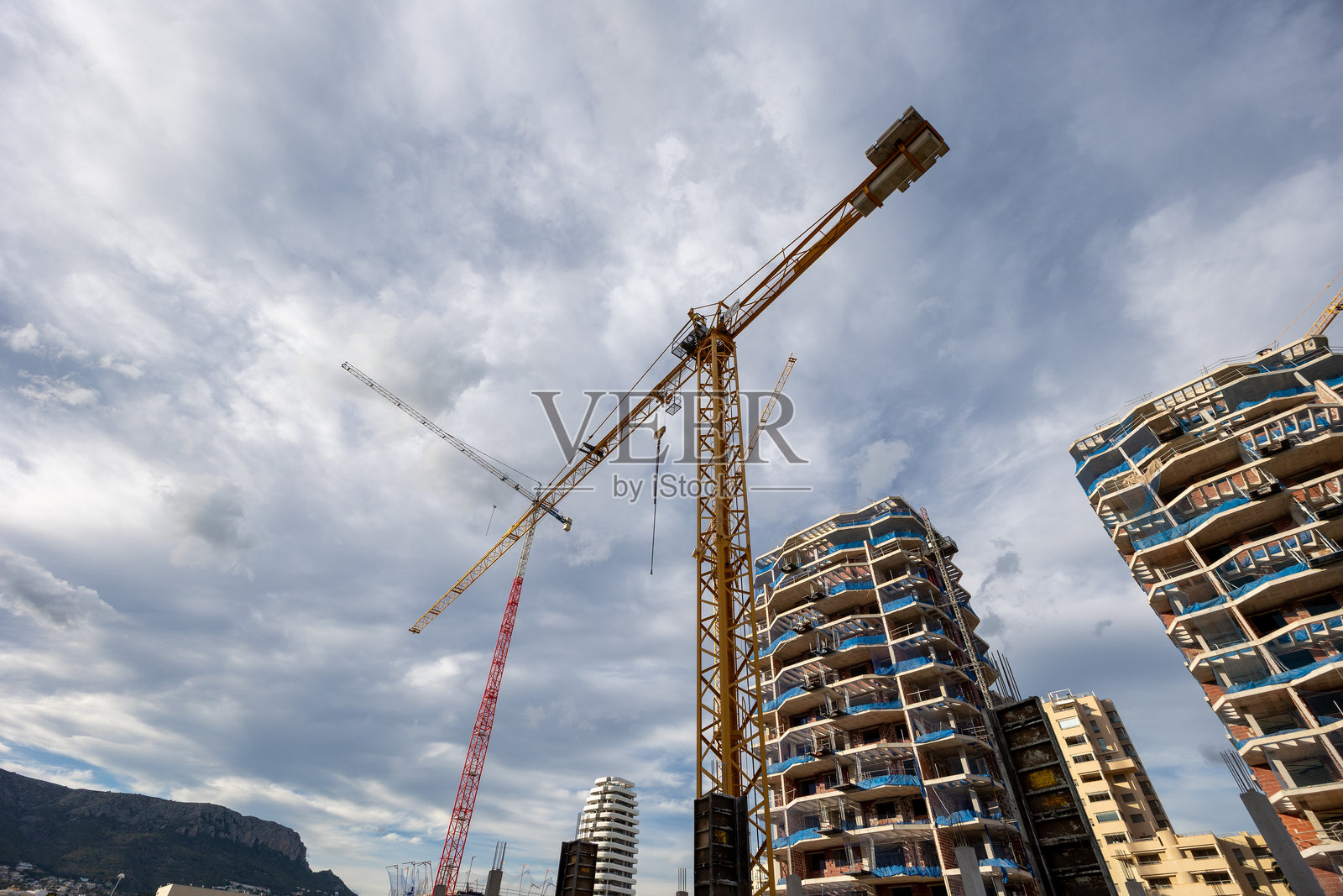 在多云的天空下，起重机正在建造现代公寓楼照片摄影图片