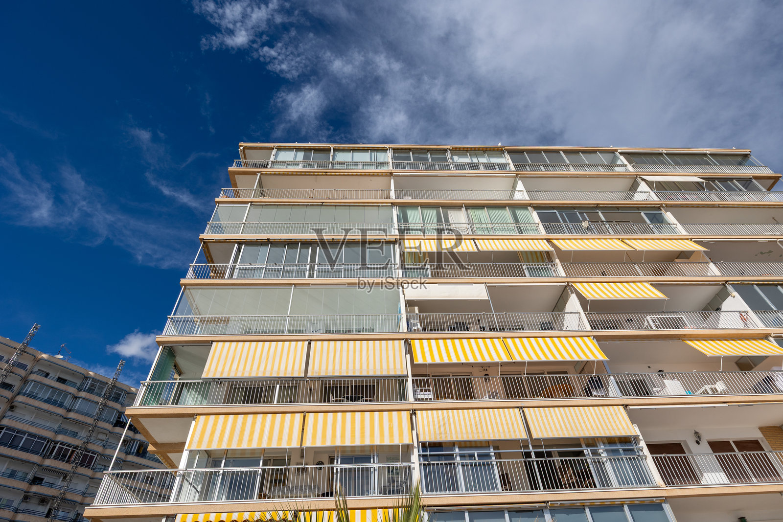 蓝天下,带有黄色遮阳篷的住宅楼外观照片摄影图片