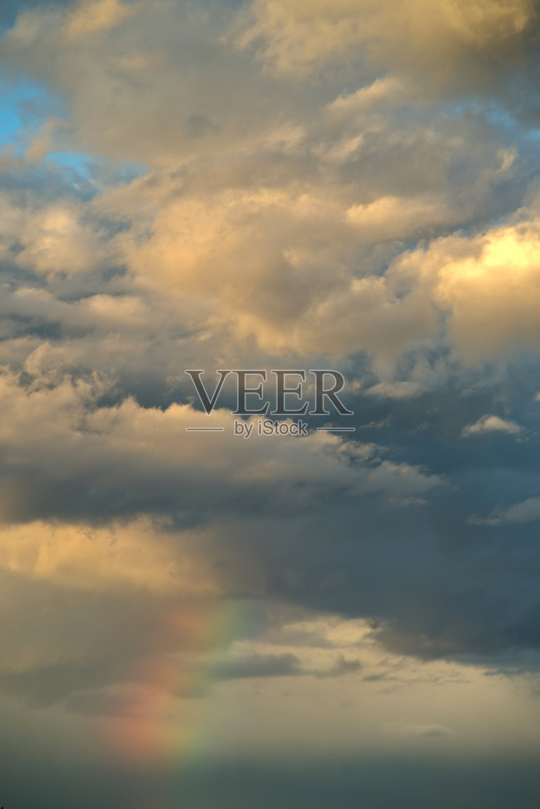 彩虹横跨山丘，出现在多云的天空下照片摄影图片