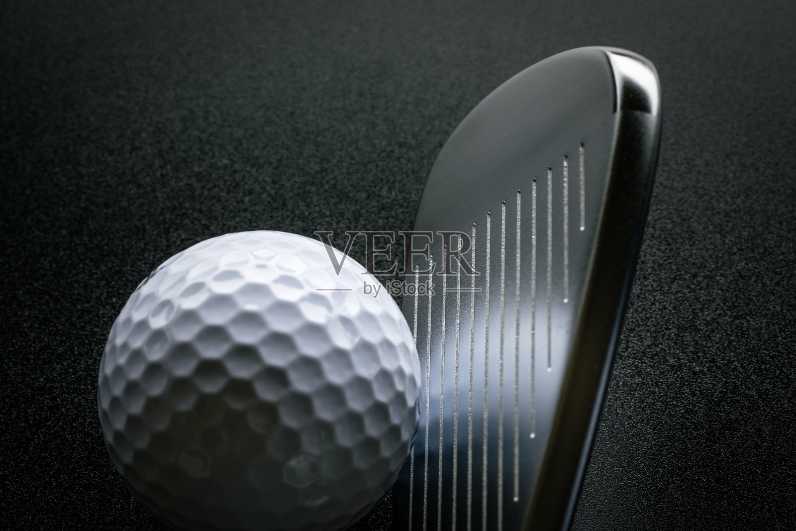 黑暗背景下，处于准备击球姿势的高尔夫球和球杆照片摄影图片