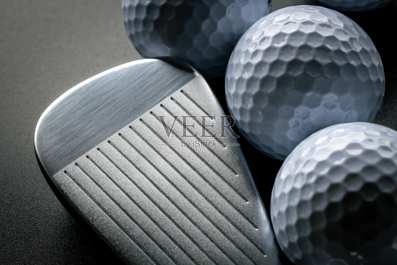 深色背景下，高尔夫球杆旁边放着高尔夫球照片摄影图片