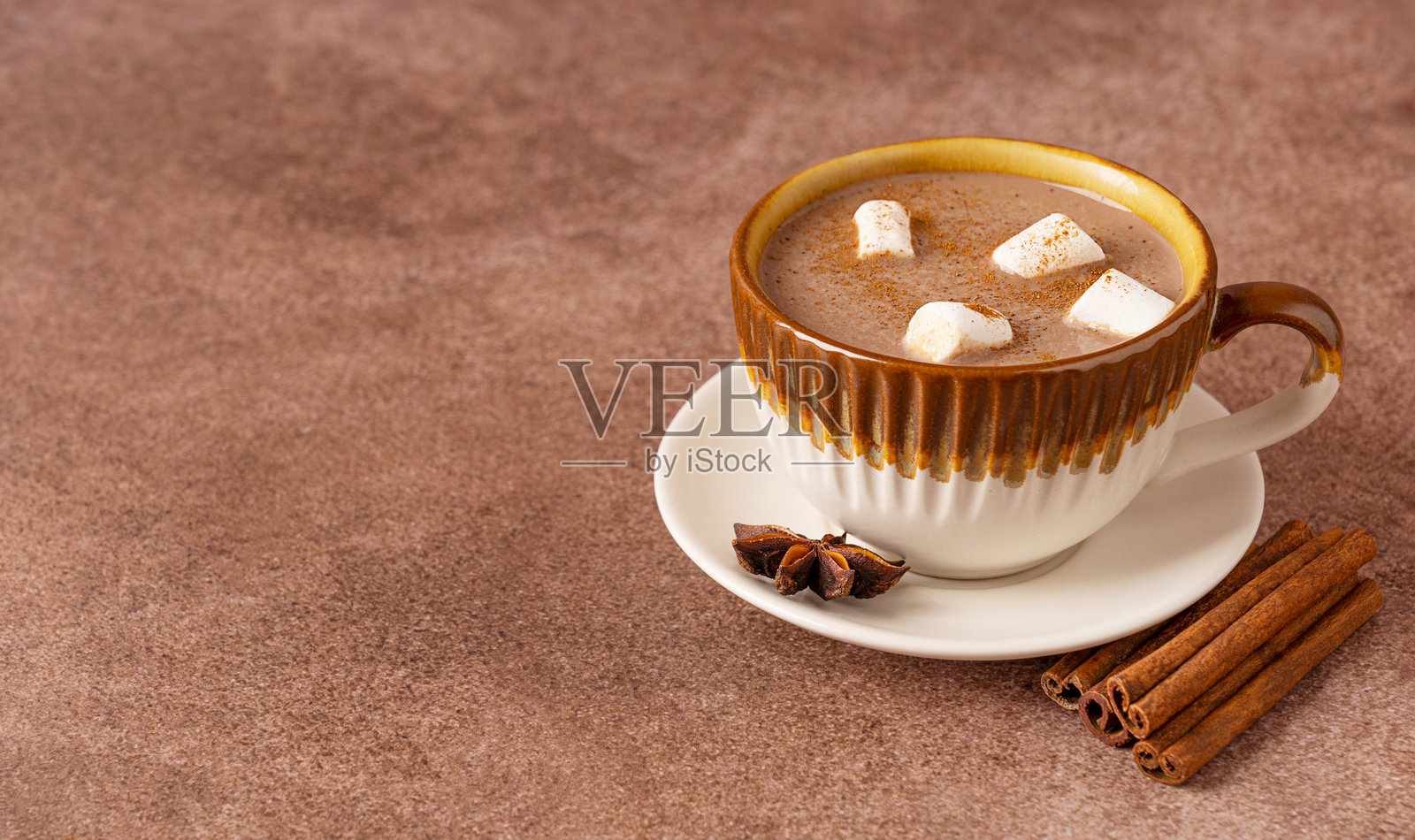 节日热巧克力饮品，配有棉花糖、肉桂和八角，放在棕色桌子上，留有复制空间照片摄影图片