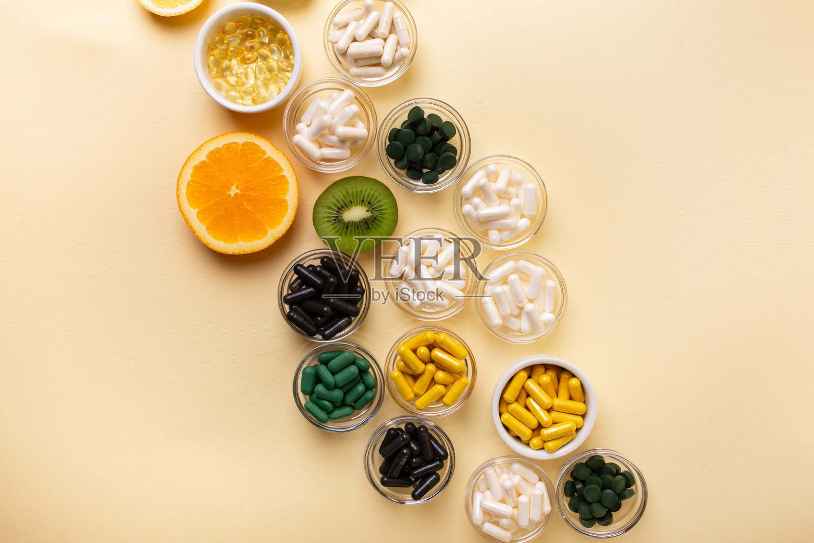 米黄色背景上的柑橘类水果、膳食补充剂、维生素和矿物质。照片摄影图片