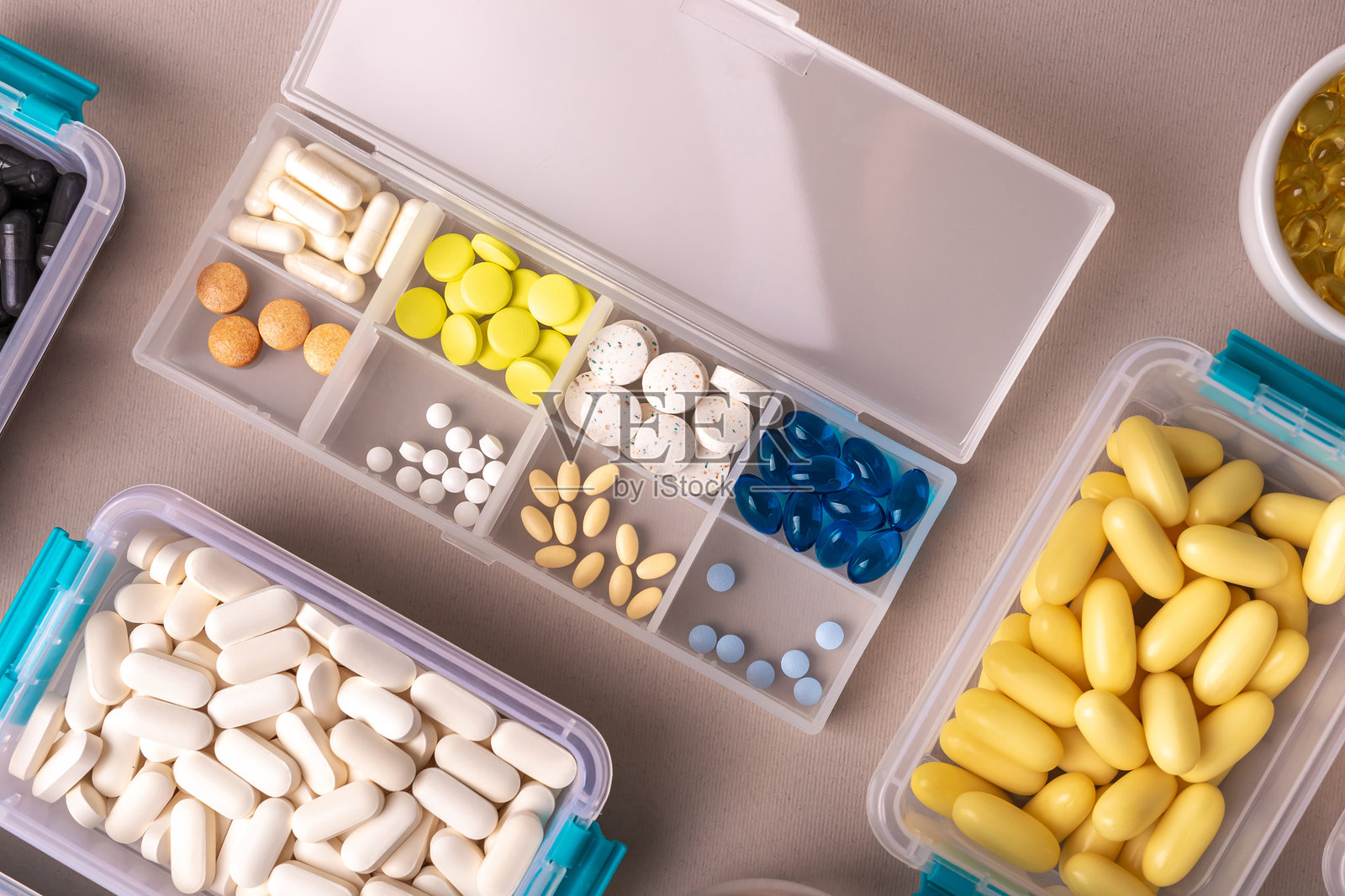 俯视角度拍摄的各种彩色维生素药瓶，放置在浅色背景上。照片摄影图片