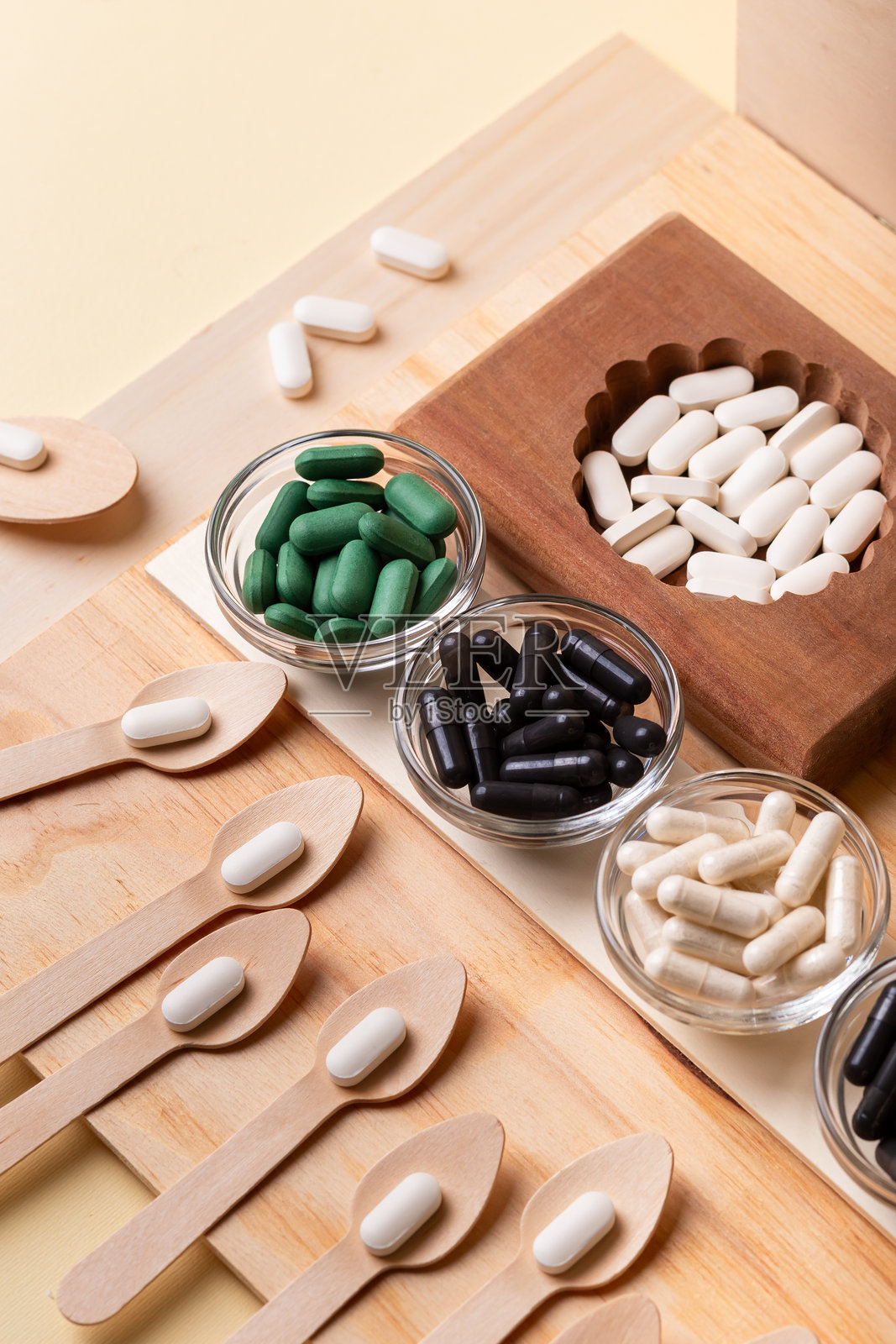许多种类的维生素、药片、膳食补充剂，装在木盒和玻璃碗里，木勺中盛有维生素。照片摄影图片