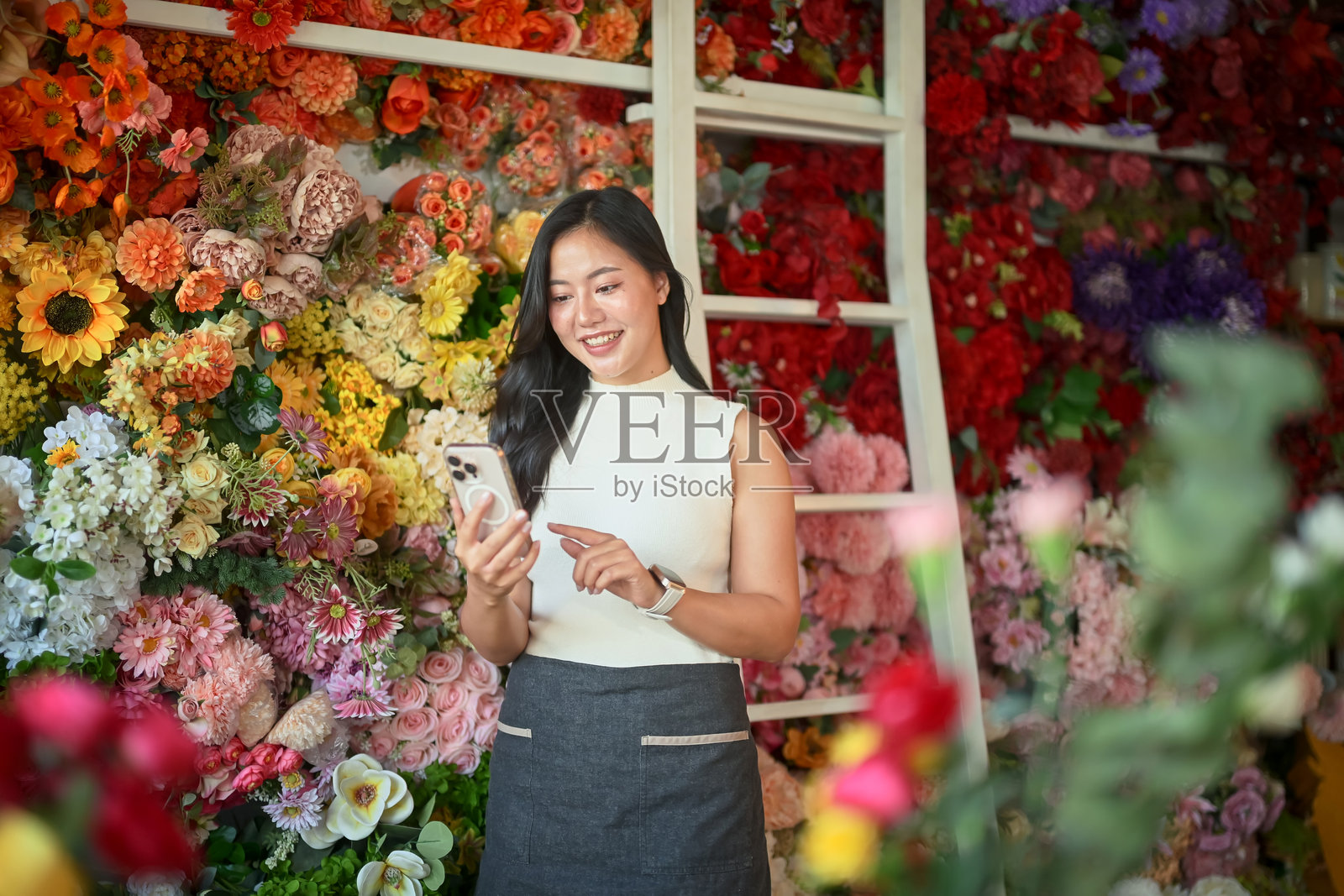 小企业主用智能手机管理鲜花库存照片摄影图片