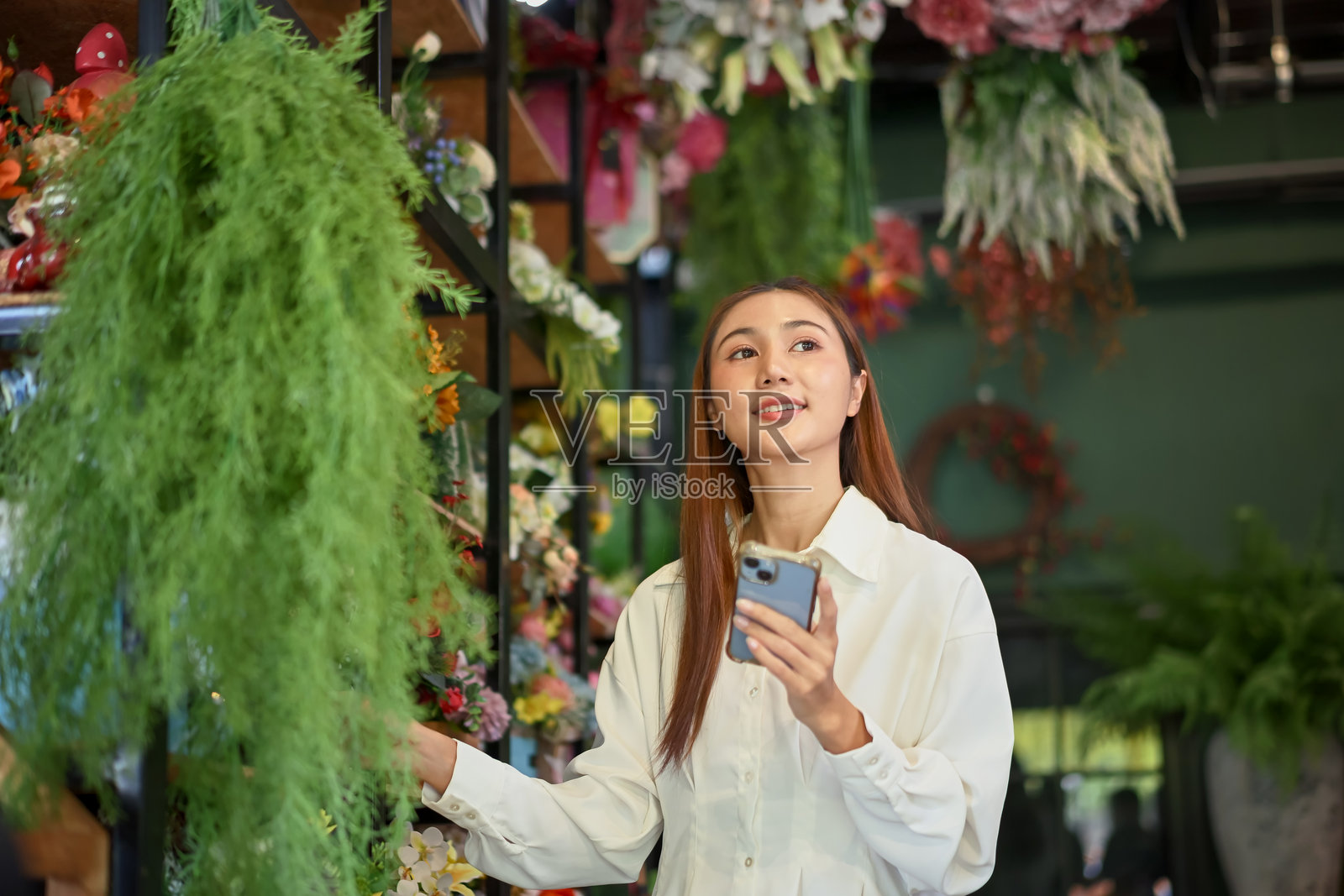 小型企业主用智能手机管理鲜花库存照片摄影图片