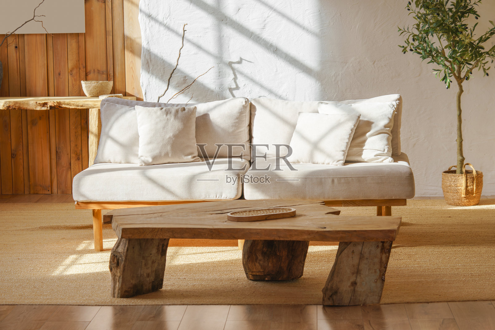 现代简约风格客厅，配有米色沙发、质朴的木桌，沐浴在自然阳光下照片摄影图片