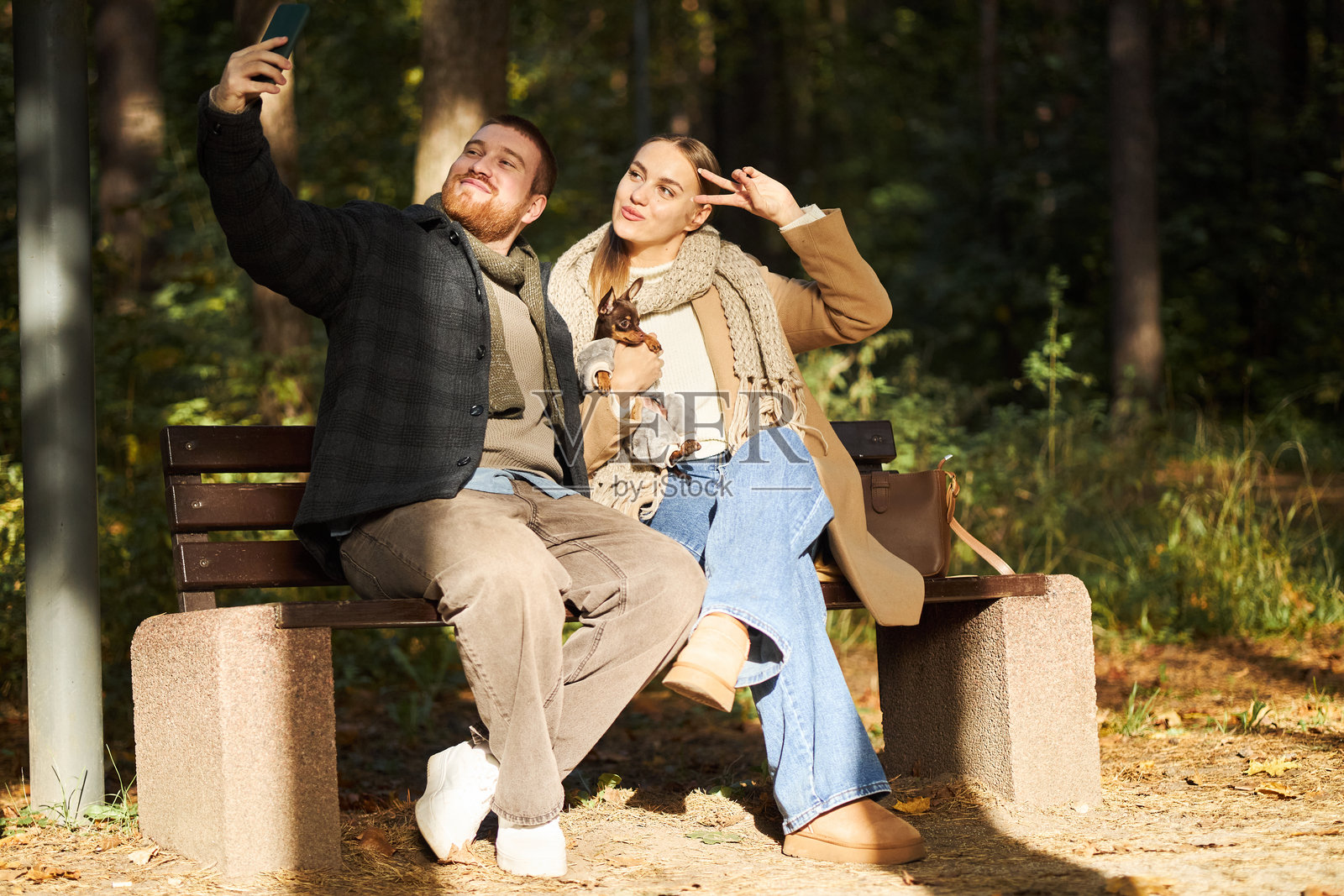 年轻夫妇和狗坐在长椅上自拍照片摄影图片