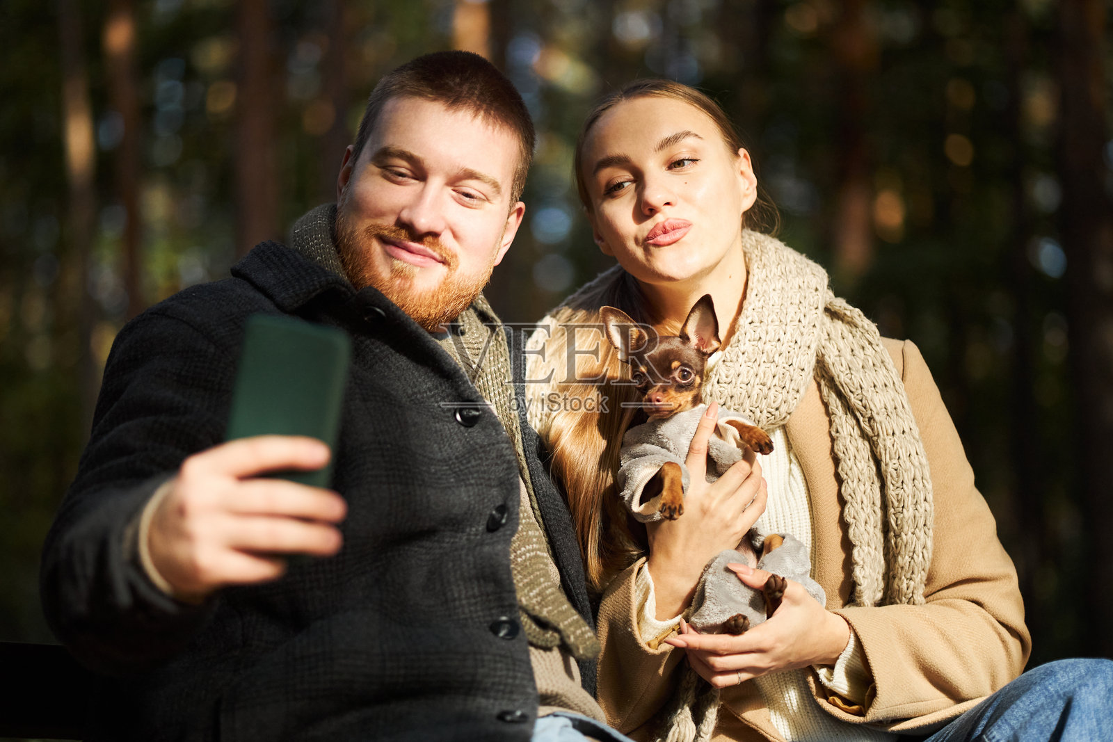 年轻男女在户外抱着小狗自拍照片摄影图片