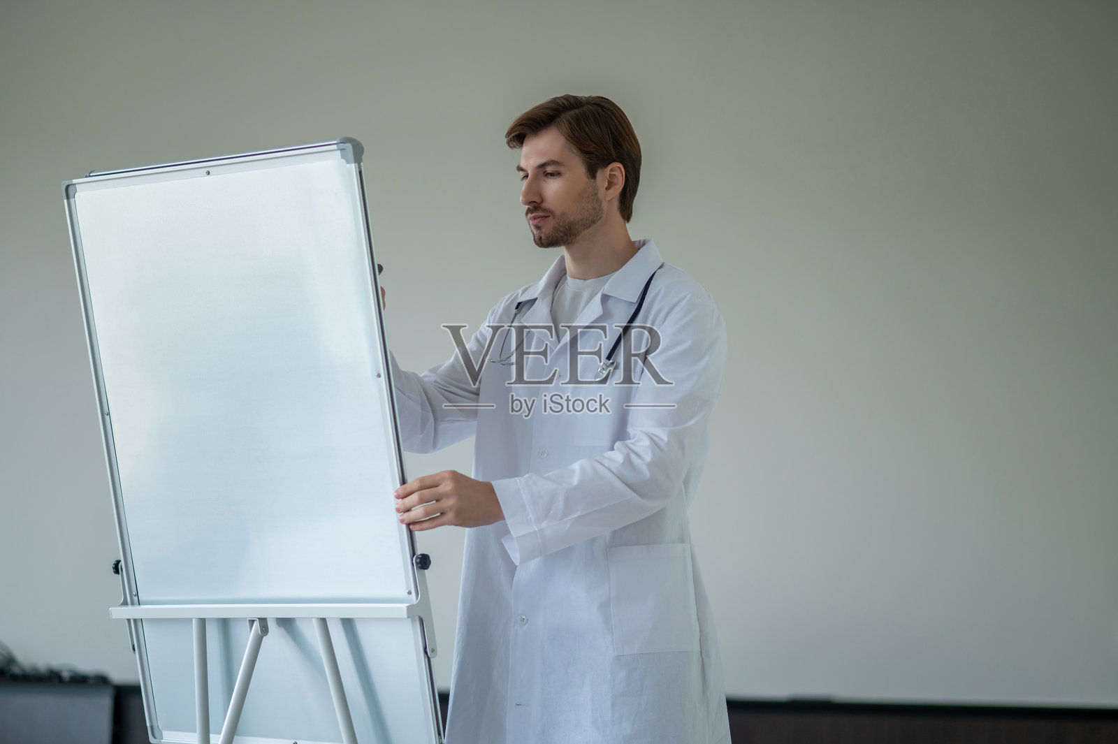 一名男医生站在便携式白色翻页图板旁，准备进行演示照片摄影图片