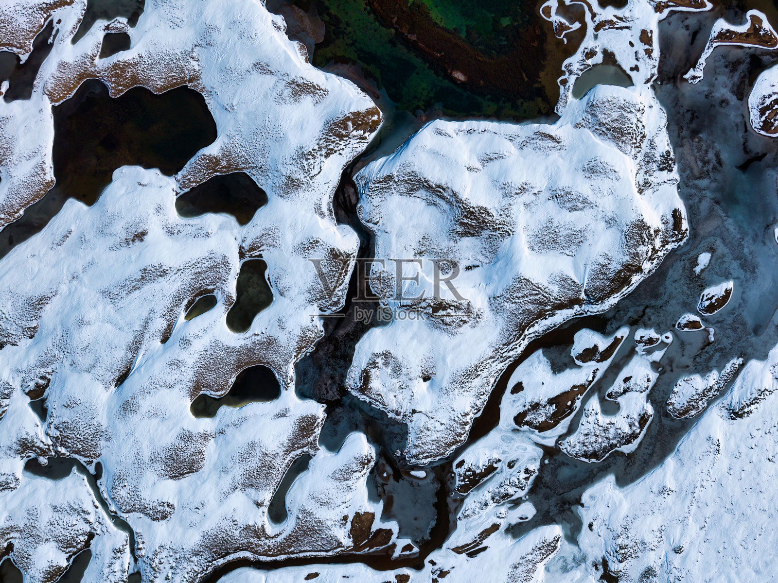 冬季偏远荒野中，覆盖着白雪的地面和蜿蜒河流的抽象自然景观照片摄影图片