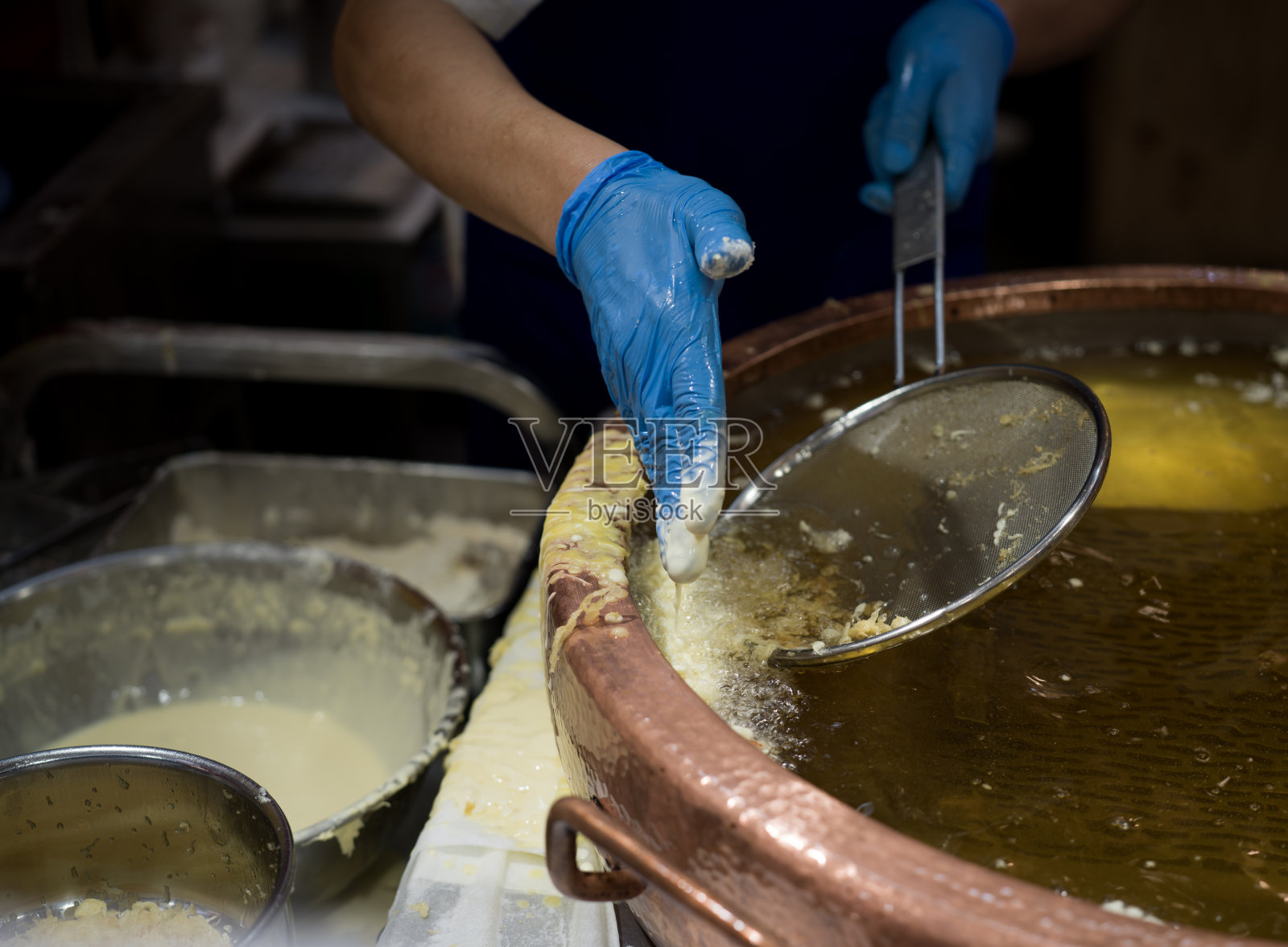 戴蓝色手套的手在热油中炸面糊照片摄影图片
