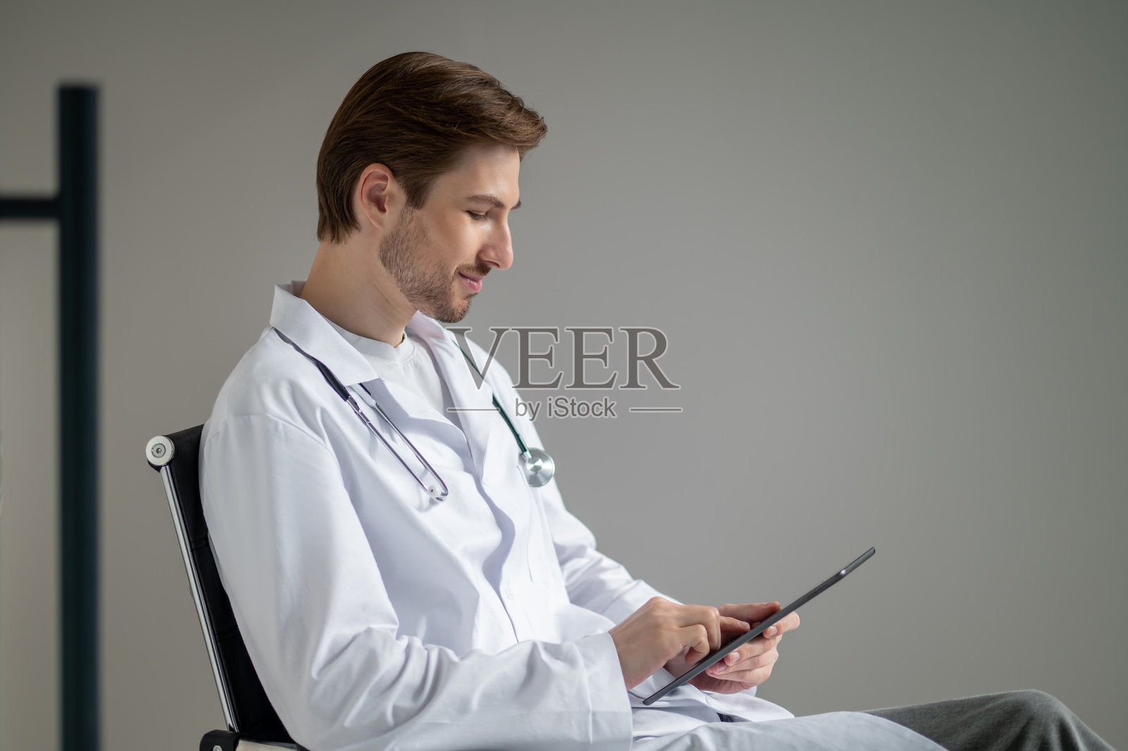 医生戴着听诊器，面带微笑，手里拿着文件夹照片摄影图片