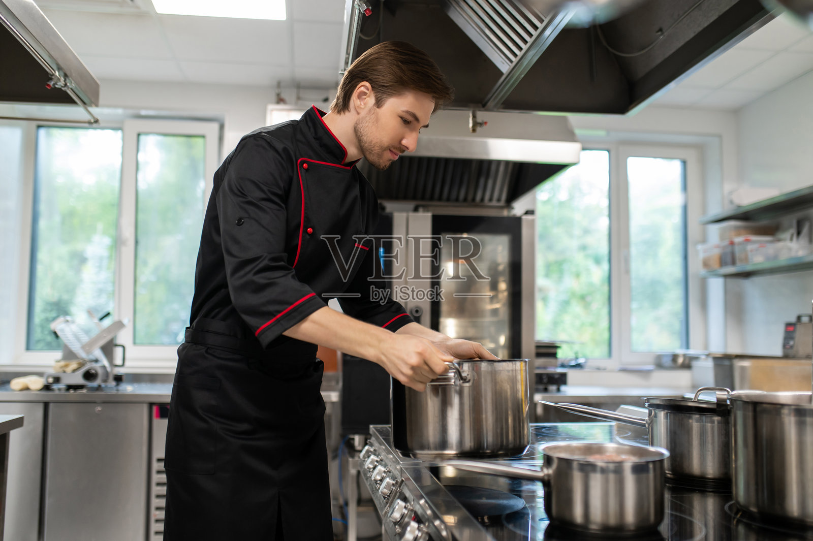 熟练的男士在厨房空间内，站在炉灶旁工作照片摄影图片