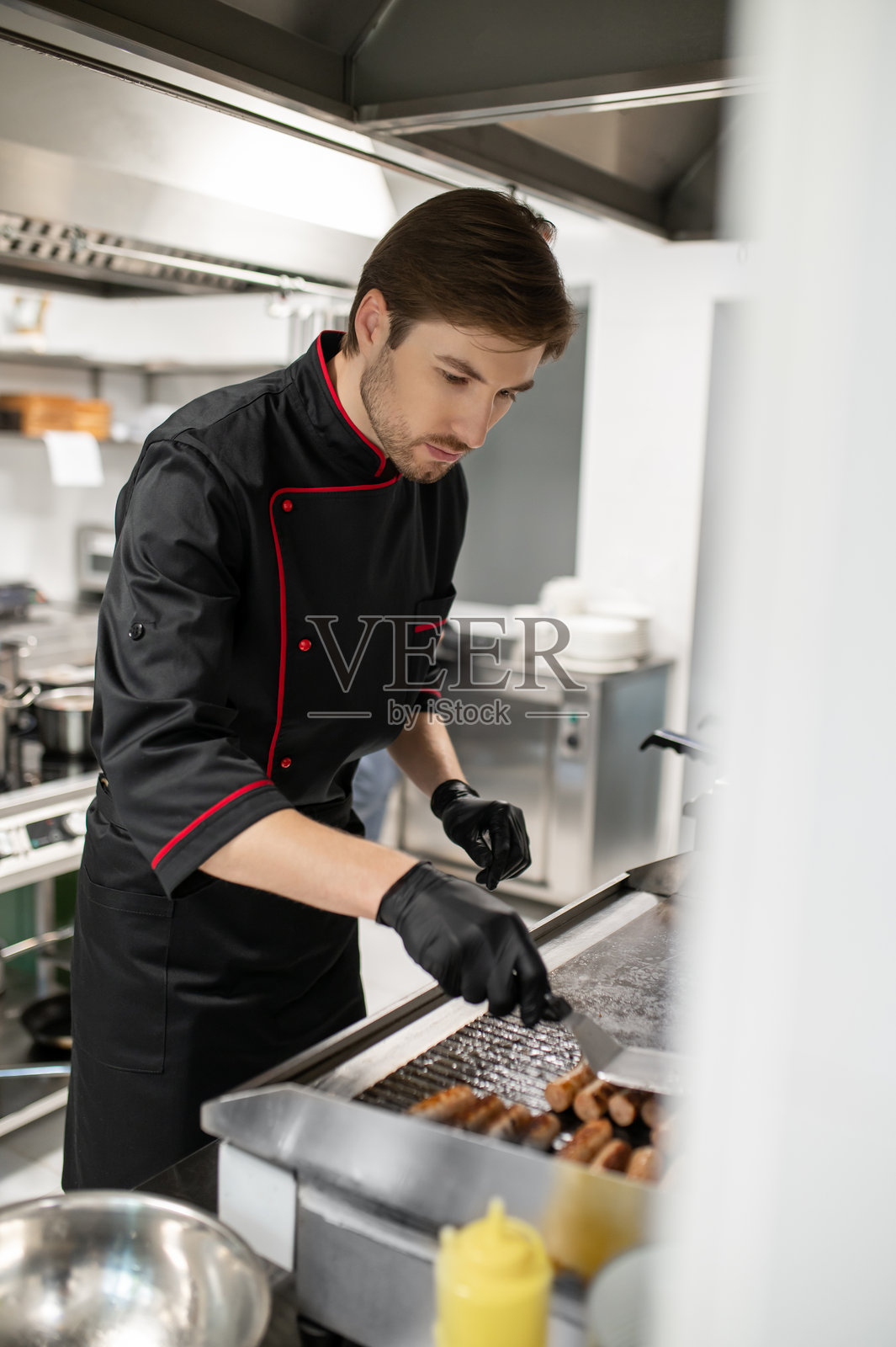 厨师在厨房的热不锈钢台面上准备香肠照片摄影图片