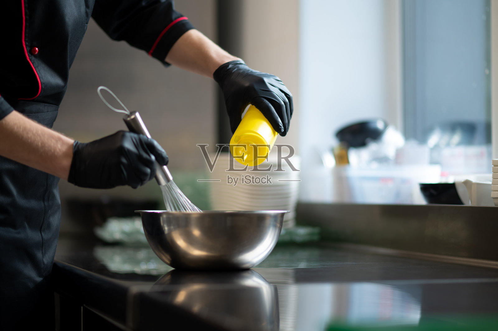 厨师将食材倒入带打蛋器的金属搅拌碗中照片摄影图片