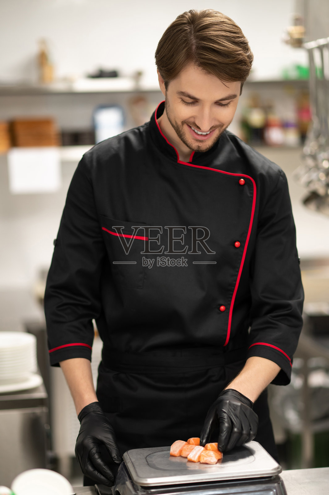 穿着制服的厨师在秤上称量三文鱼份量照片摄影图片