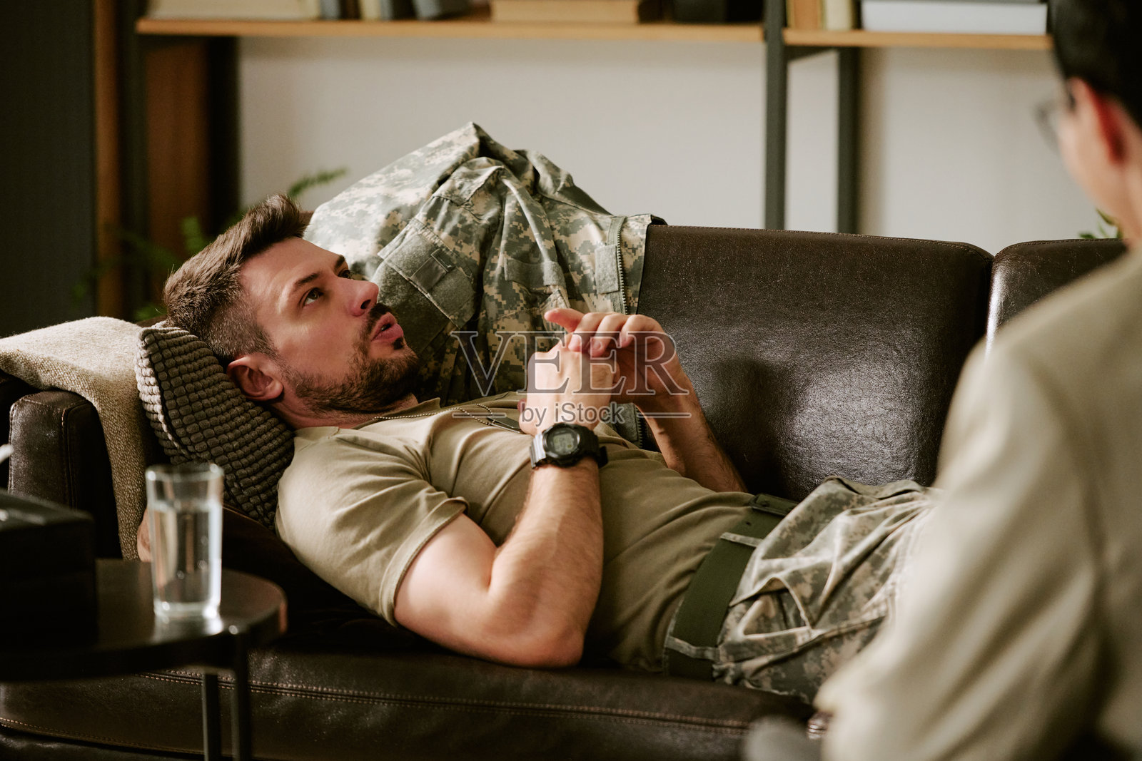 年轻的白人男性躺在沙发上，与心理医生讨论问题照片摄影图片