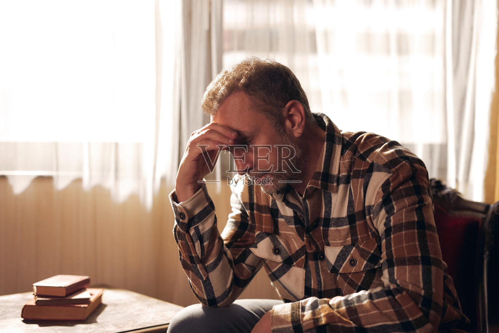 一名患有抑郁症并头痛的男子在家中坐着。照片摄影图片