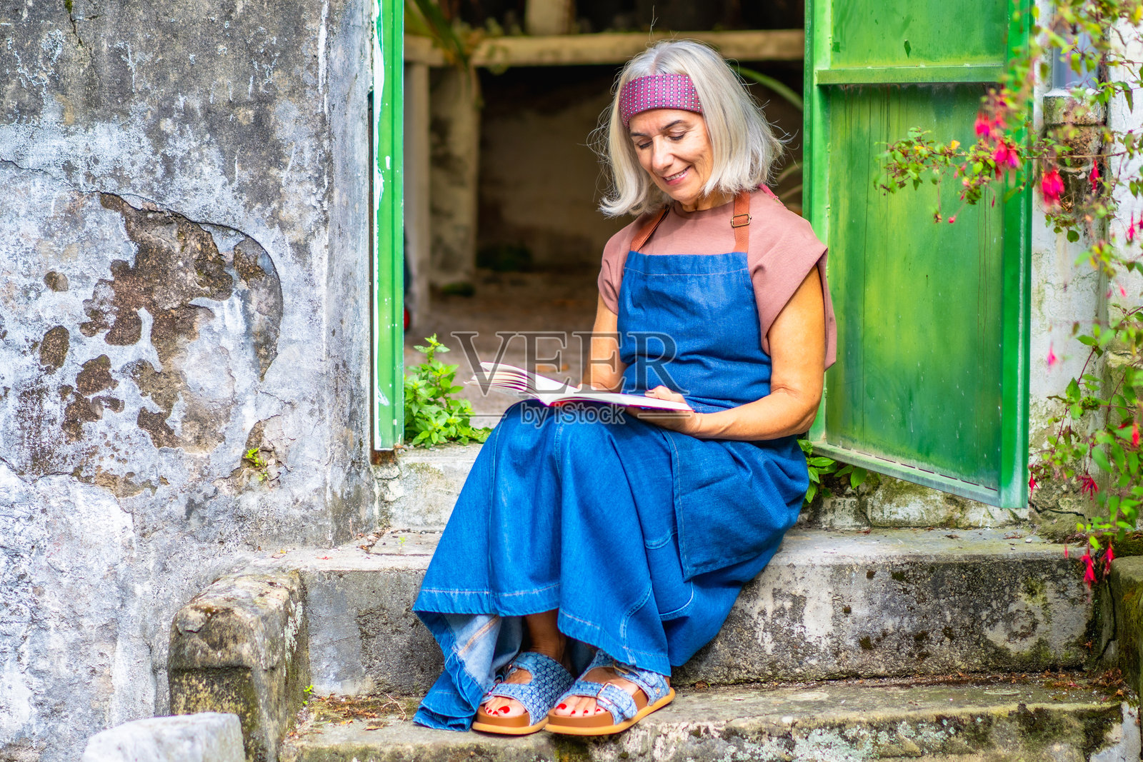 一位年长的女性在石阶上放松地阅读书籍照片摄影图片