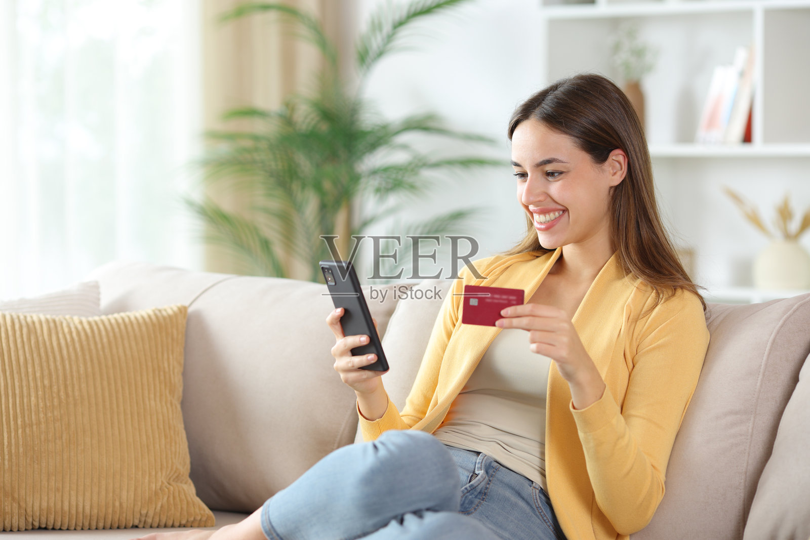 快乐的黄衣女子在家网上购物照片摄影图片