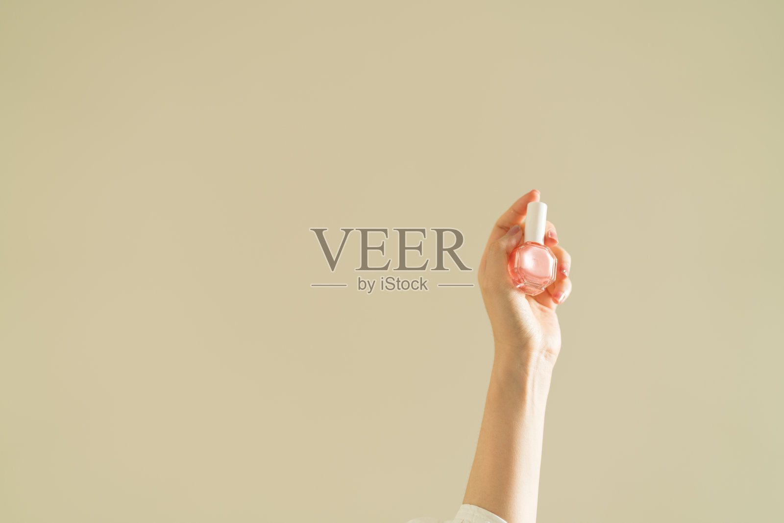 女性的手拿着粉色指甲油。照片摄影图片