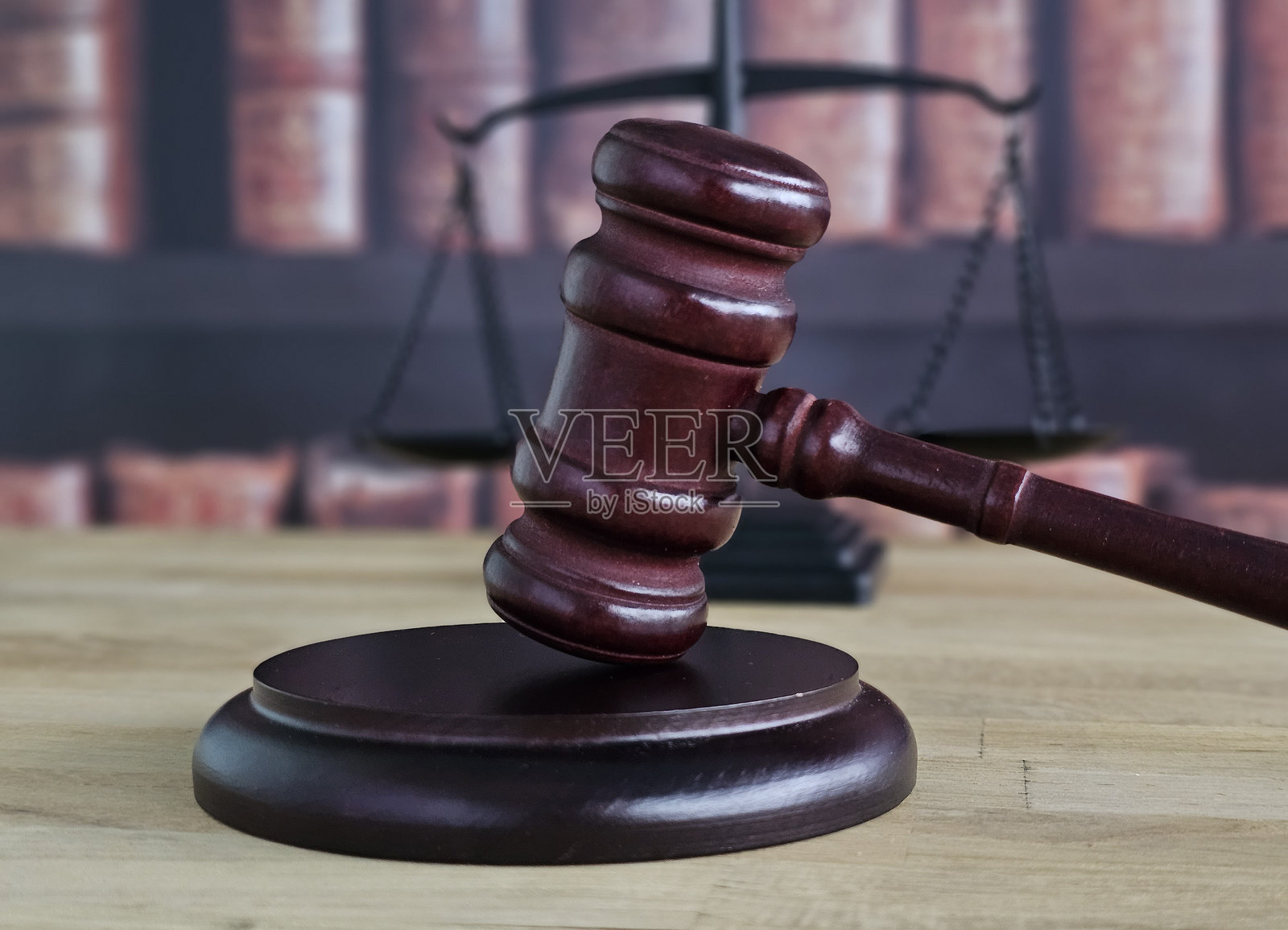 象征法律的书本背景前，一个带有圆形底座的法槌和天平照片摄影图片