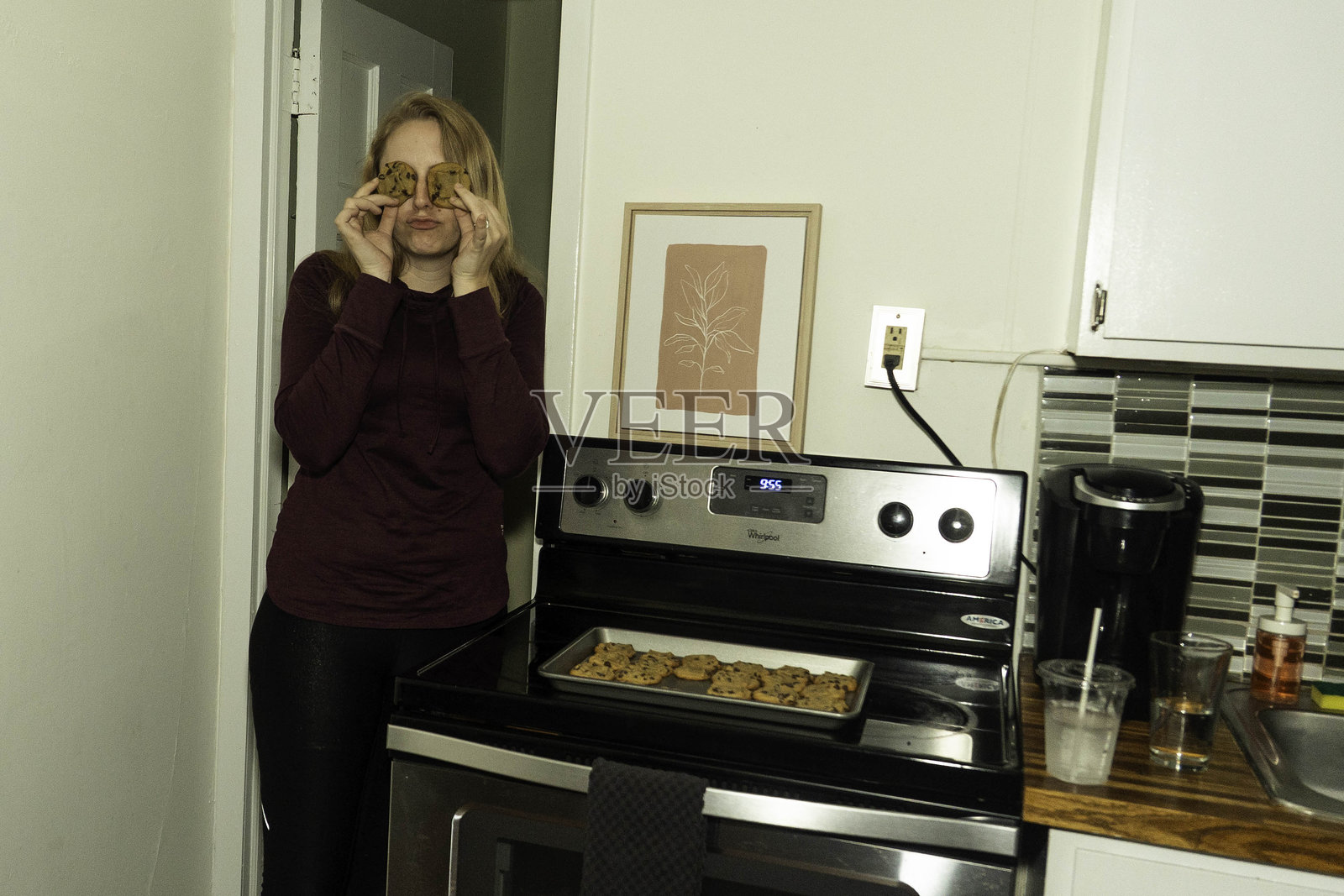 快乐的家庭烘焙师在家，身穿围裙的愉悦女子在温馨的厨房里为亲人烘焙新鲜的饼干照片摄影图片