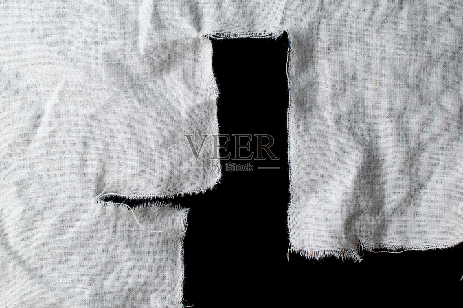撕裂的白色旧抹布，上面有洞，背景为黑色，画布照片摄影图片
