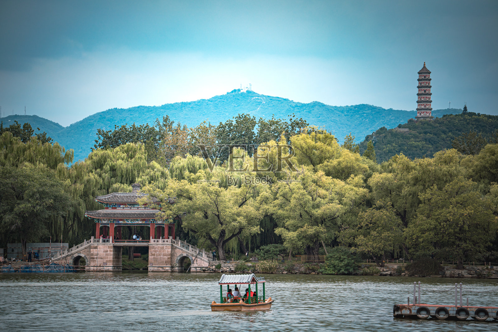 一座令人惊叹的夏季宫殿景象。图片捕捉了古老建筑的细节，坐落于宁静的湖泊和充满活力的绿植之间，背景是连绵的山峦。天空多云，光线 Perfect。照片摄影图片