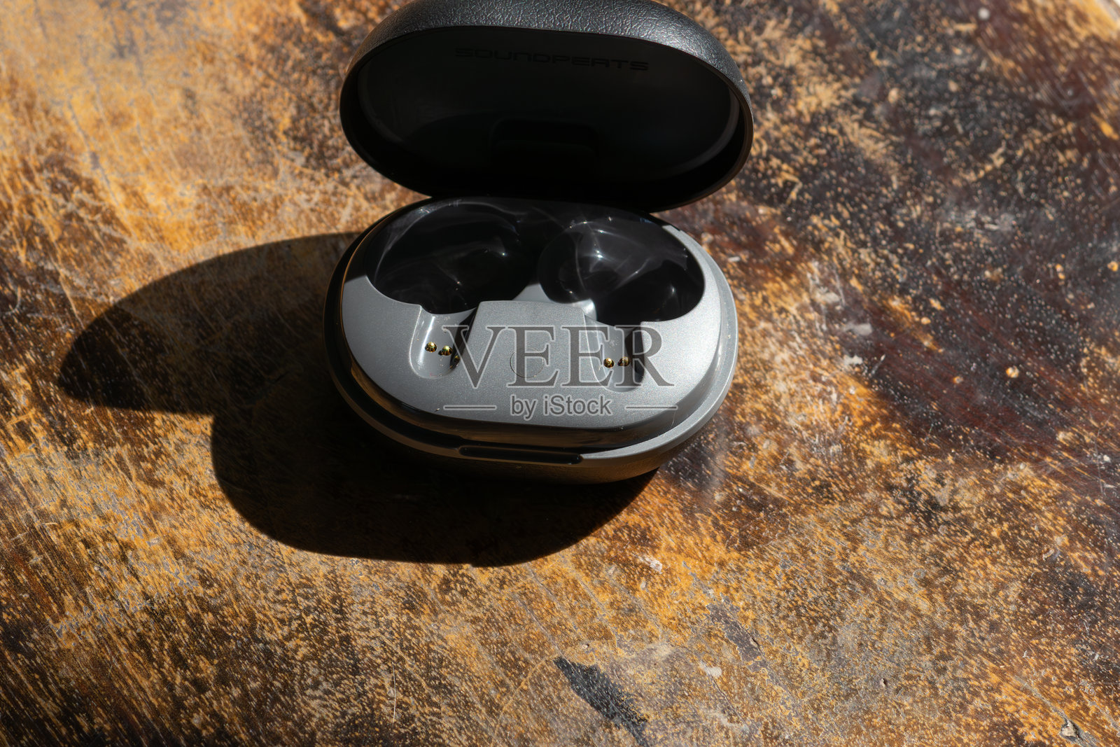 无线耳机充电盒放在质朴的木纹上。照片摄影图片