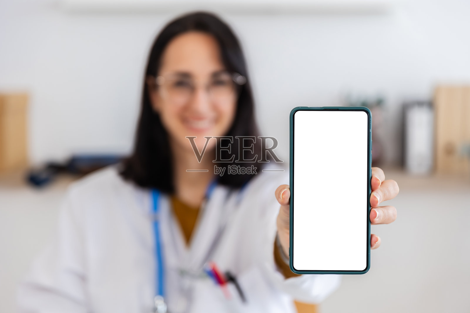身穿医疗服的专业人士手持带有空白屏幕的智能手机，用于模型展示。照片摄影图片