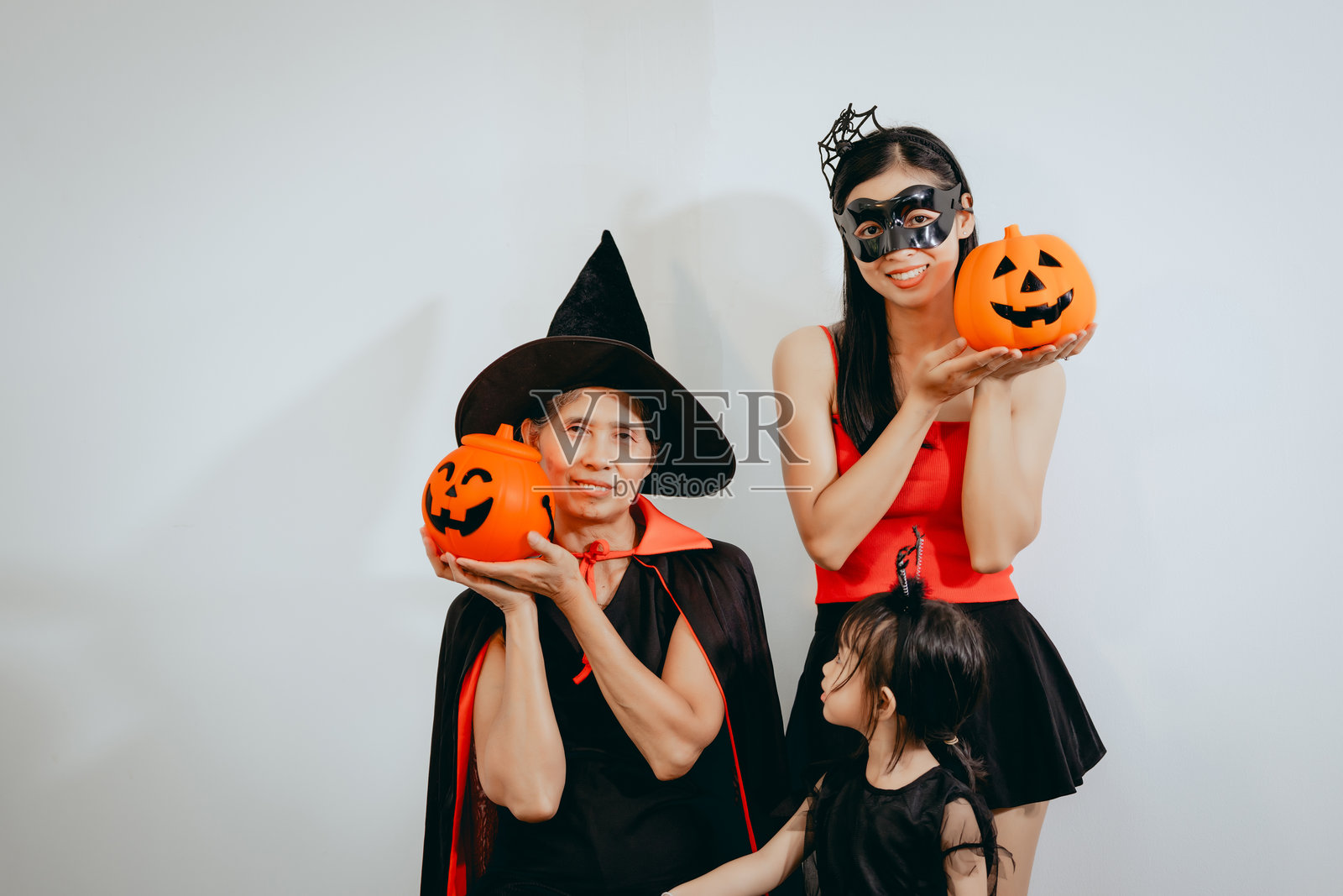 一位亚裔母亲、她可爱的女儿和打扮成女巫的祖母一起庆祝万圣节，享受充满欢乐、服装、节日气氛的温馨家庭时光。照片摄影图片