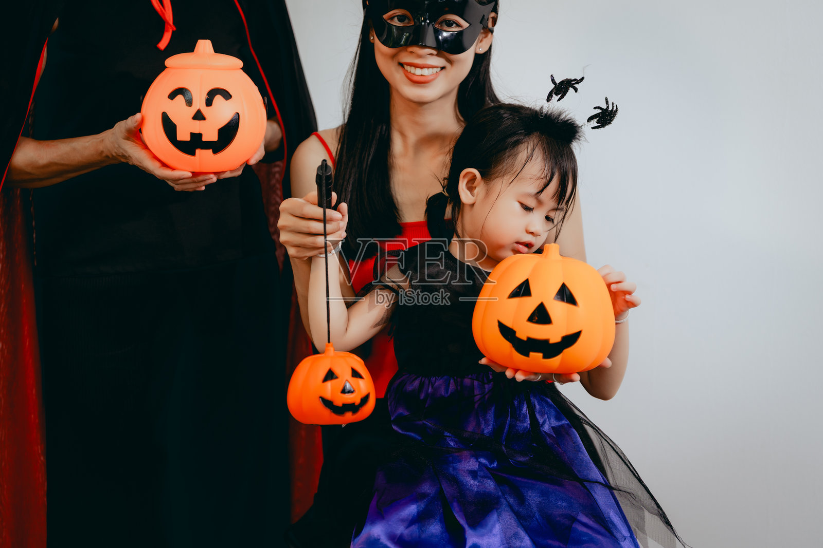 一位亚裔母亲、她可爱的女儿以及打扮成女巫的祖母一起庆祝万圣节，享受充满欢乐、服装和节日气氛的温馨家庭时光。照片摄影图片