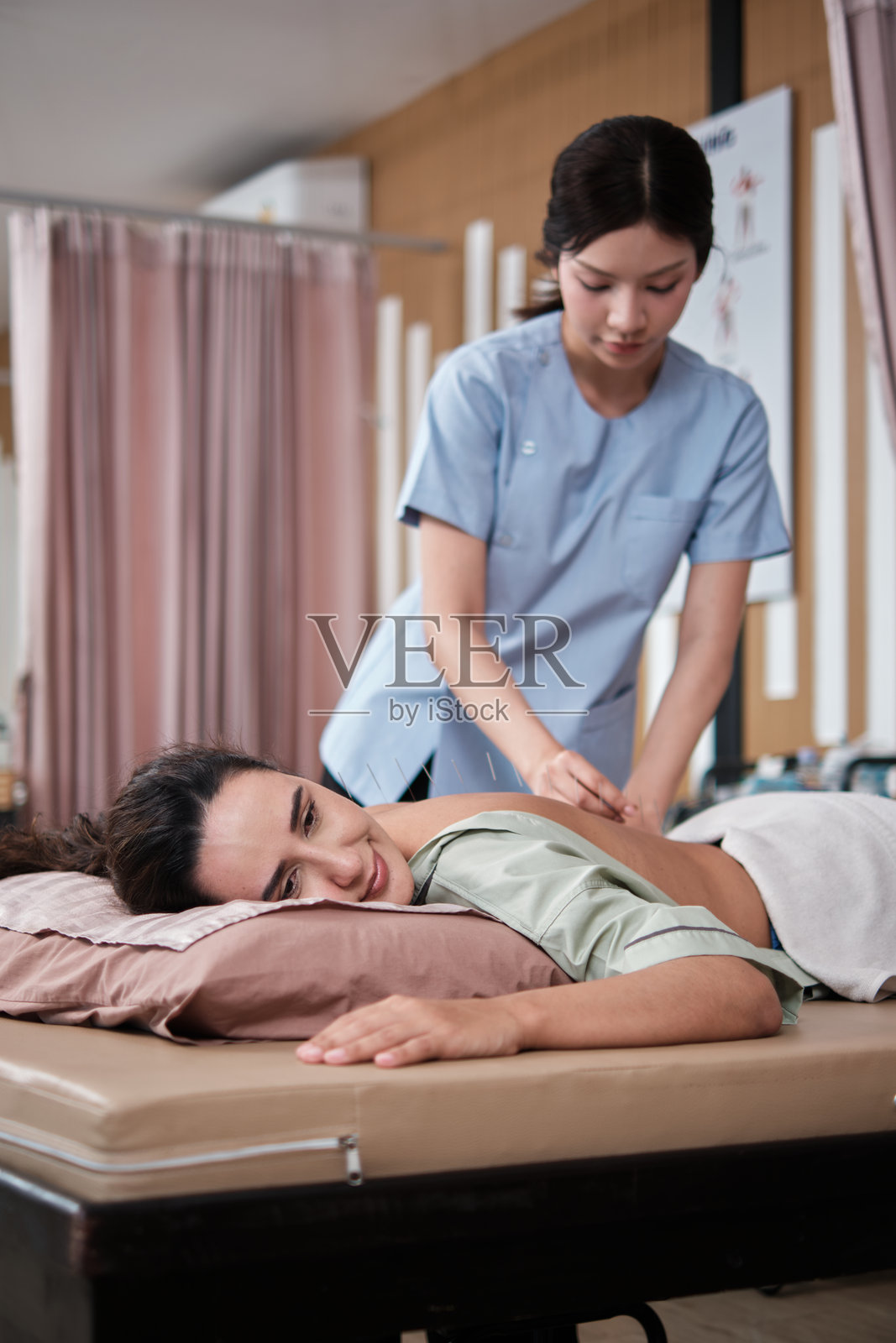 物理治疗师用针灸治愈了拉丁裔女患者的背痛。照片摄影图片