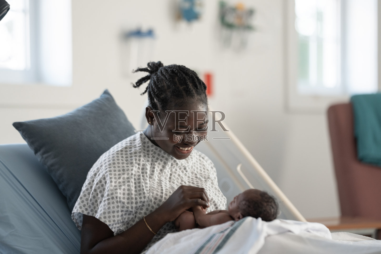 初为人母的喜悦：一位黑人母亲在医院产房中轻抚新生儿照片摄影图片