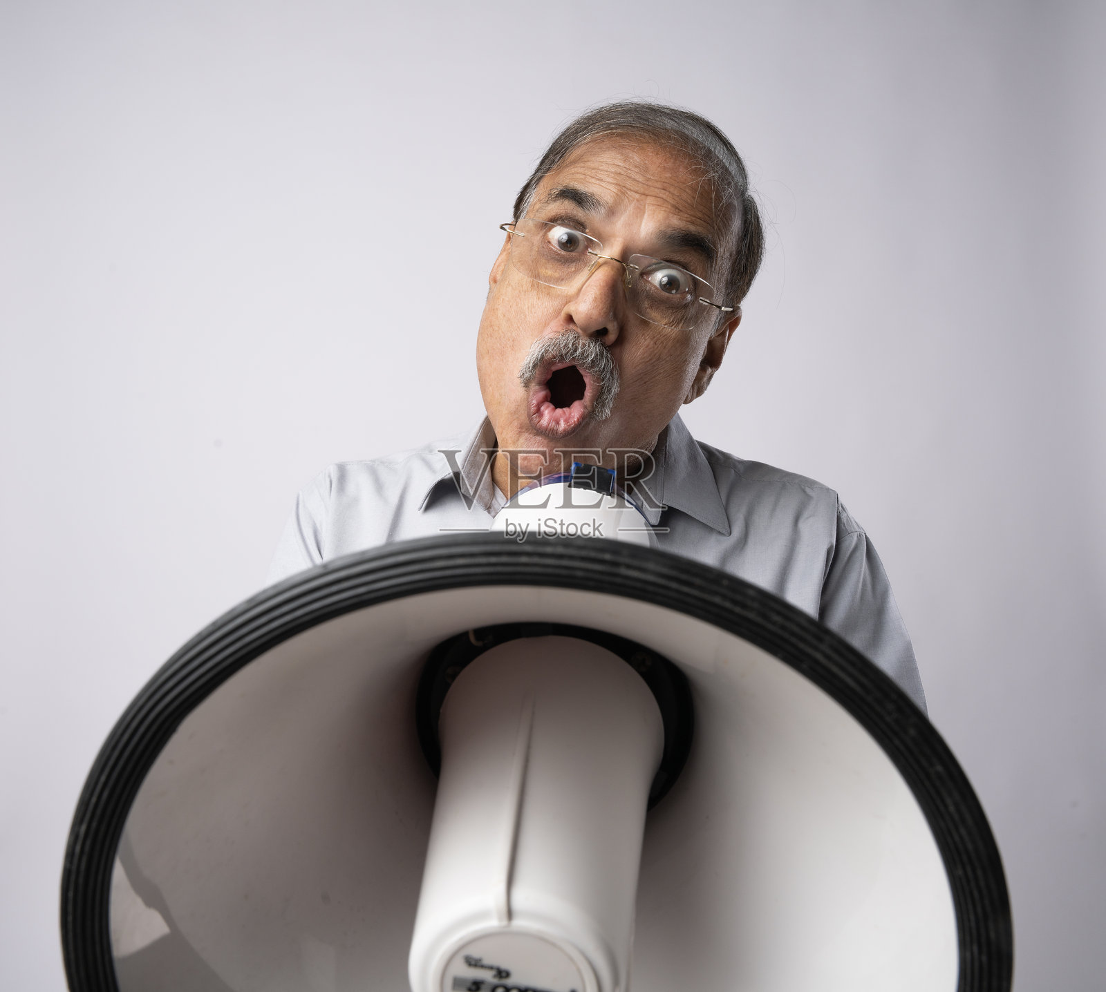 愤怒的老人拿着扩音器在白色背景上大喊照片摄影图片