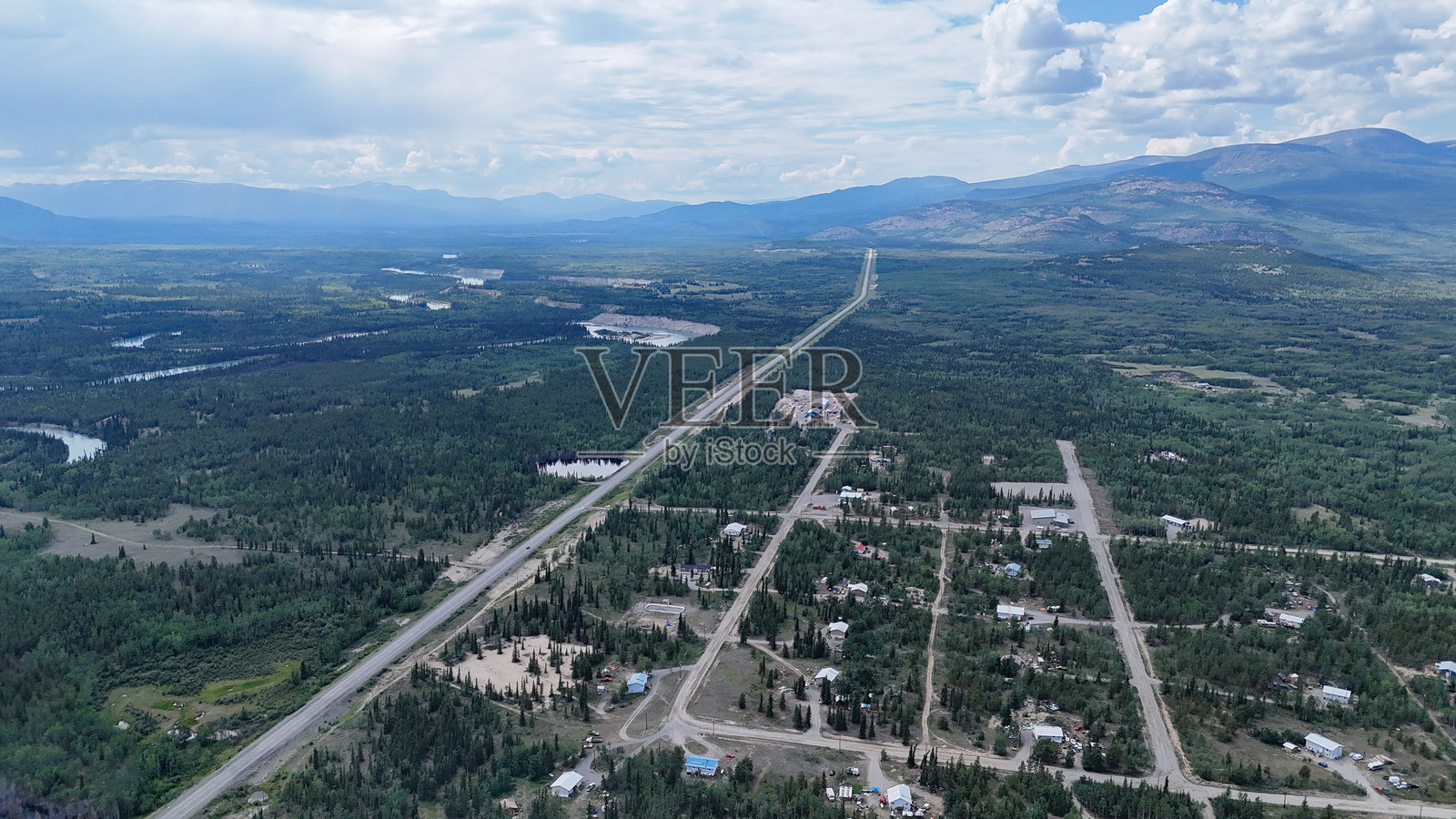 壮观的航拍视角，展现了一个偏远社区坐落于广阔的森林景观之中，远处是连绵的山峦，捕捉了乡村生活和风景之美。照片摄影图片